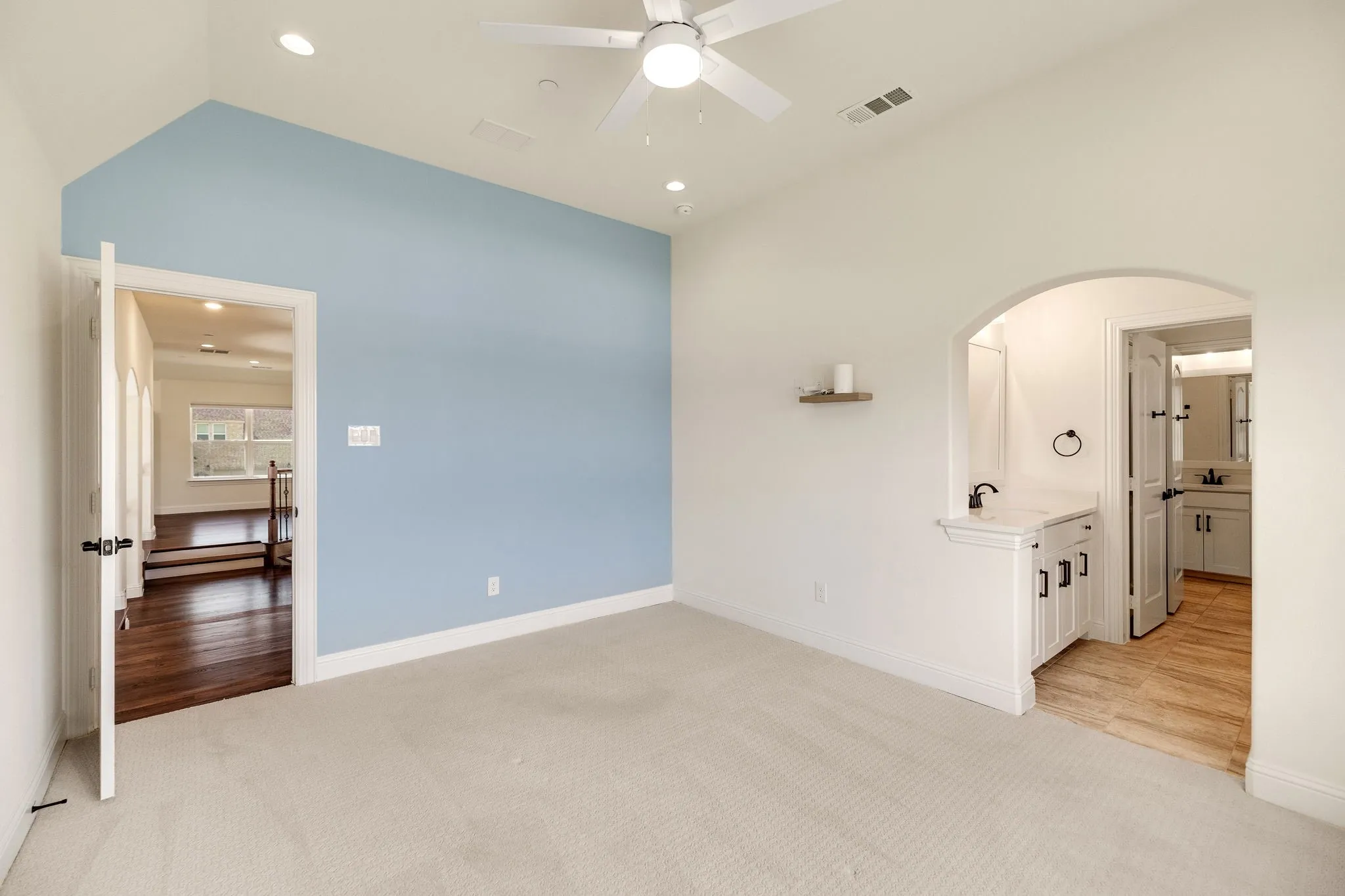 Vaulted ceiling, ceiling fan, recessed lighting, built-in wet bar with cabinet storage, and an arched entry