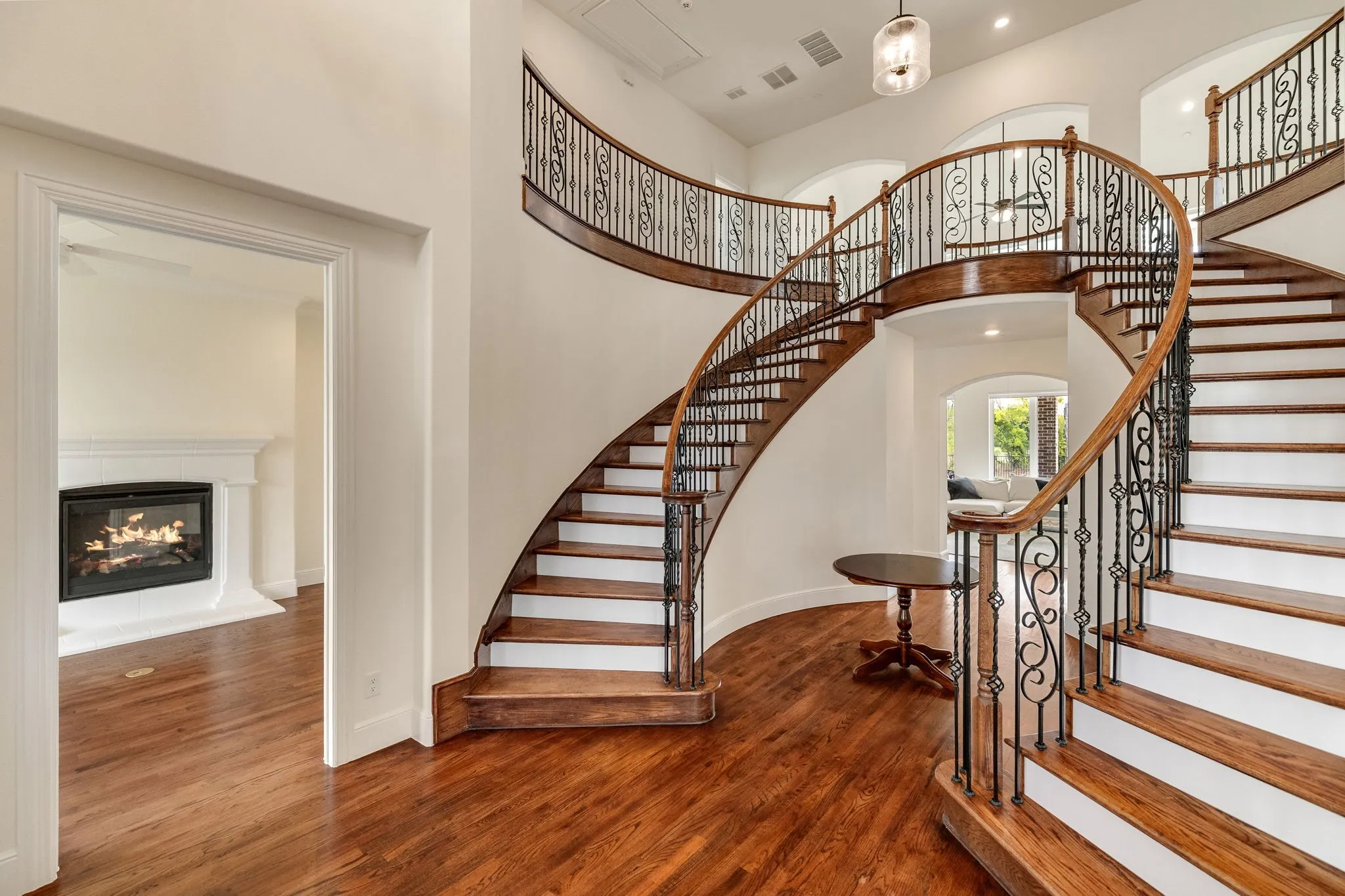 Grand curved staircase featuring wood treads and wrought iron balusters