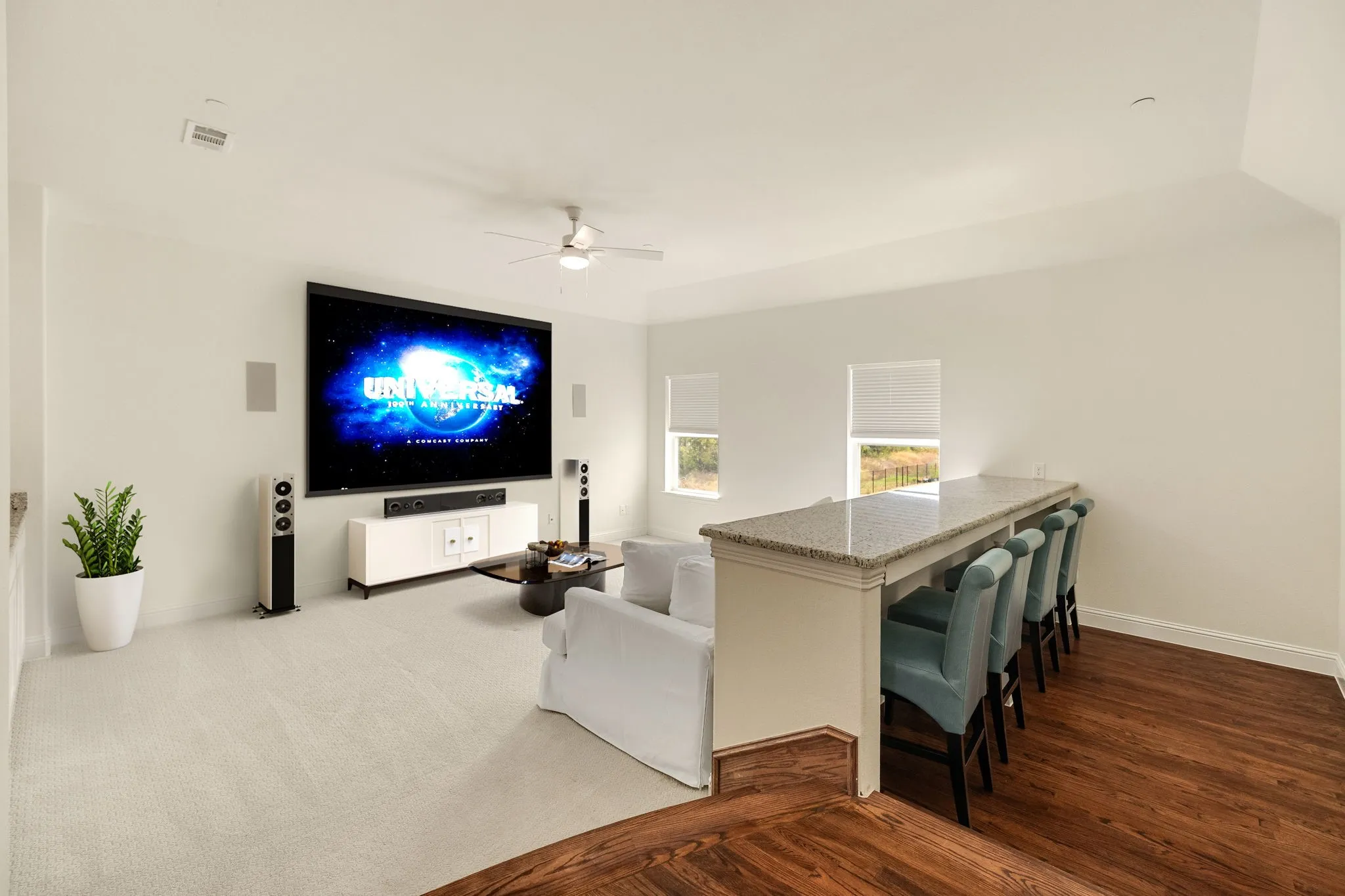 Media room virtually staged, Media room featuring a large projection screen, recessed wall speakers, and a ceiling fan