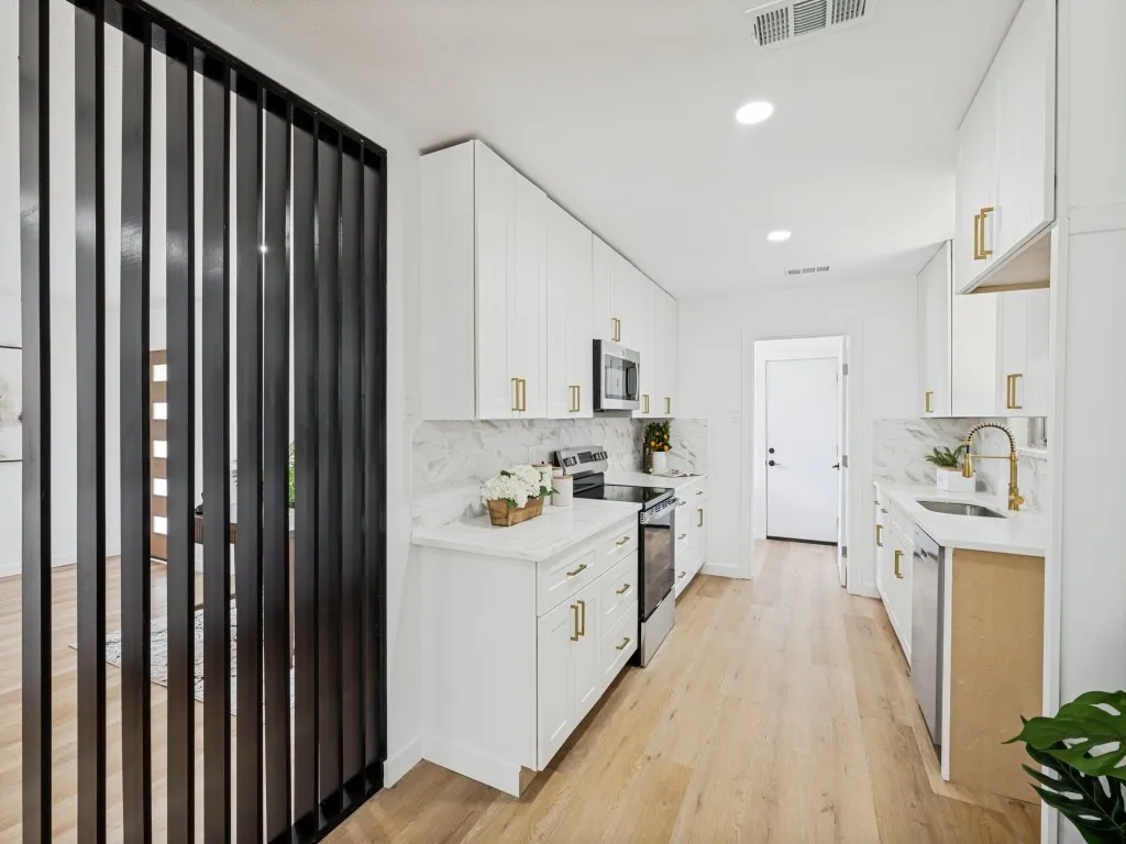 Galley kitchen featuring white cabinetry, light-toned wood-finish flooring, white countertops, and a marble-patterned backsplash
