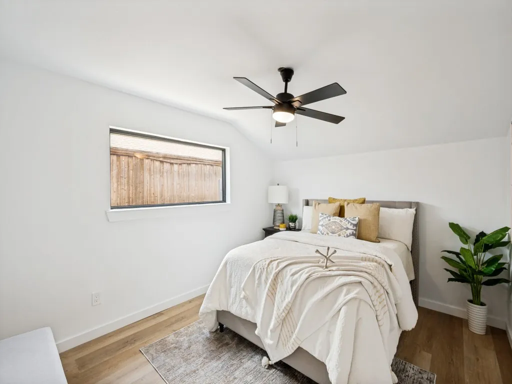 Vaulted ceiling with a ceiling fan and integrated lighting, wood-finish flooring, and white walls