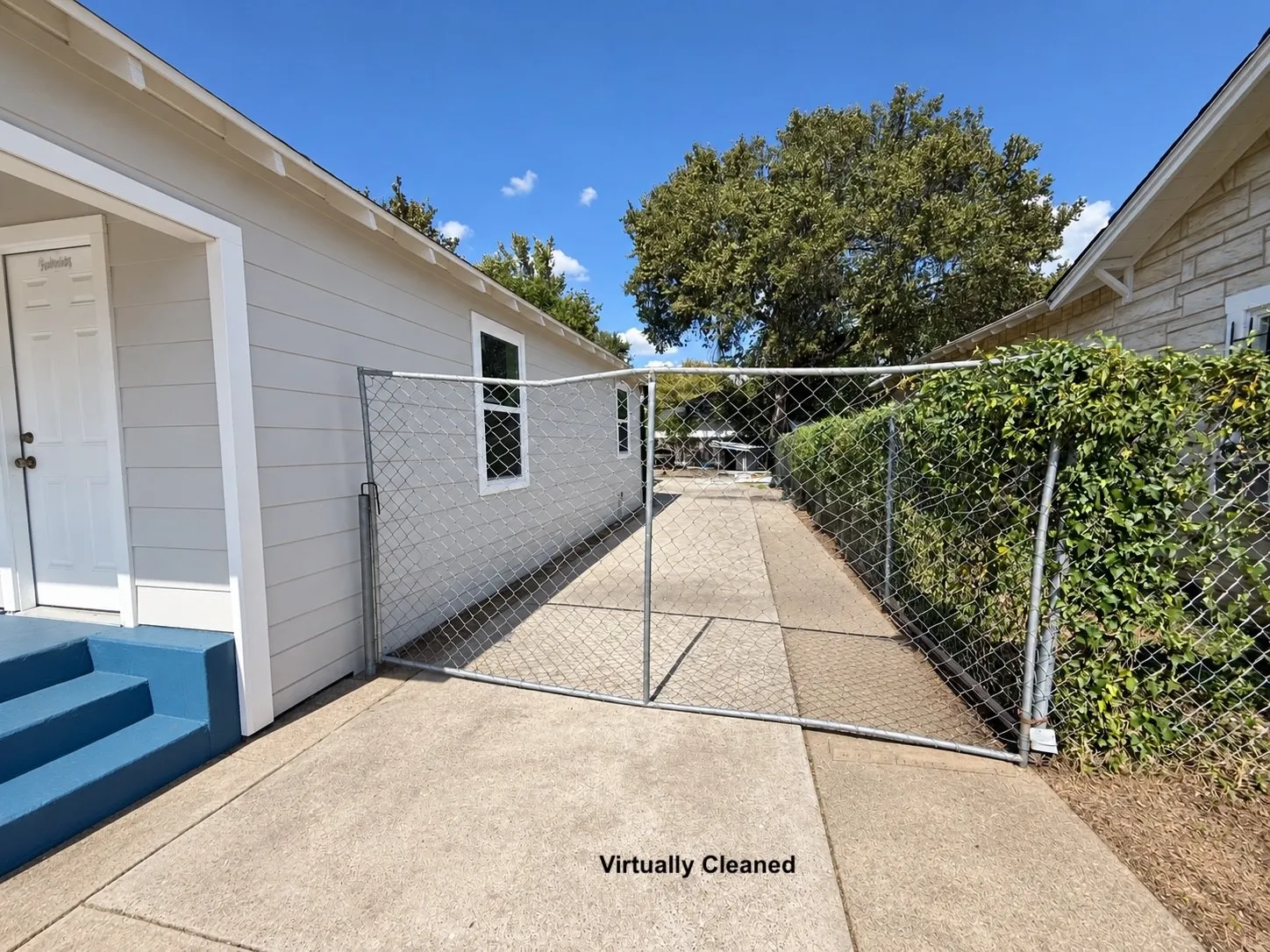 Chain-link fence with gate, concrete pathway, and mature perimeter greenery
