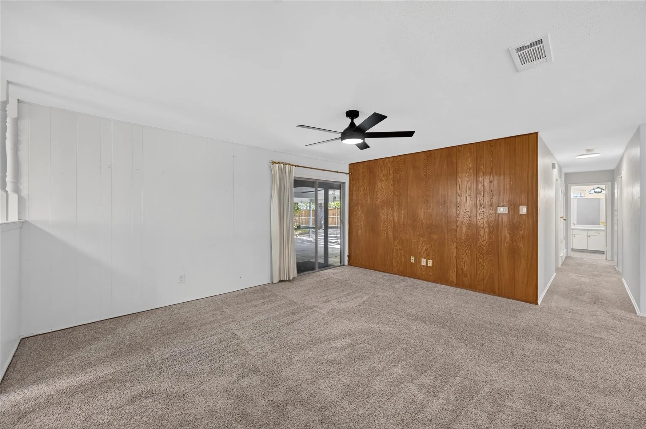 Spacious living room with sliding glass door to the backyard. hallway leads to the bedrooms and bathrooms