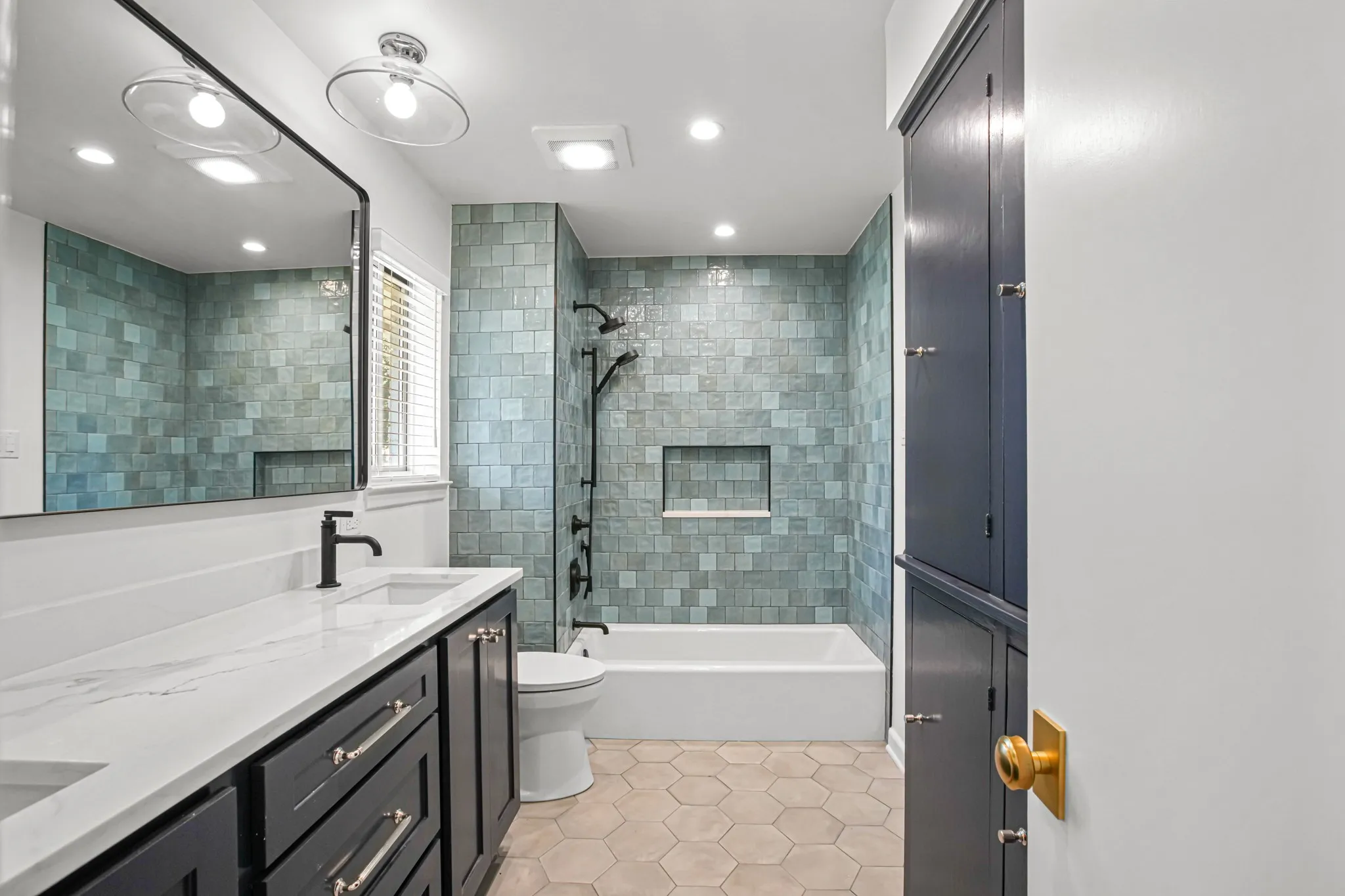 Jack-n-Jill bath with navy cabinets, quartz counters and zellige style tile.