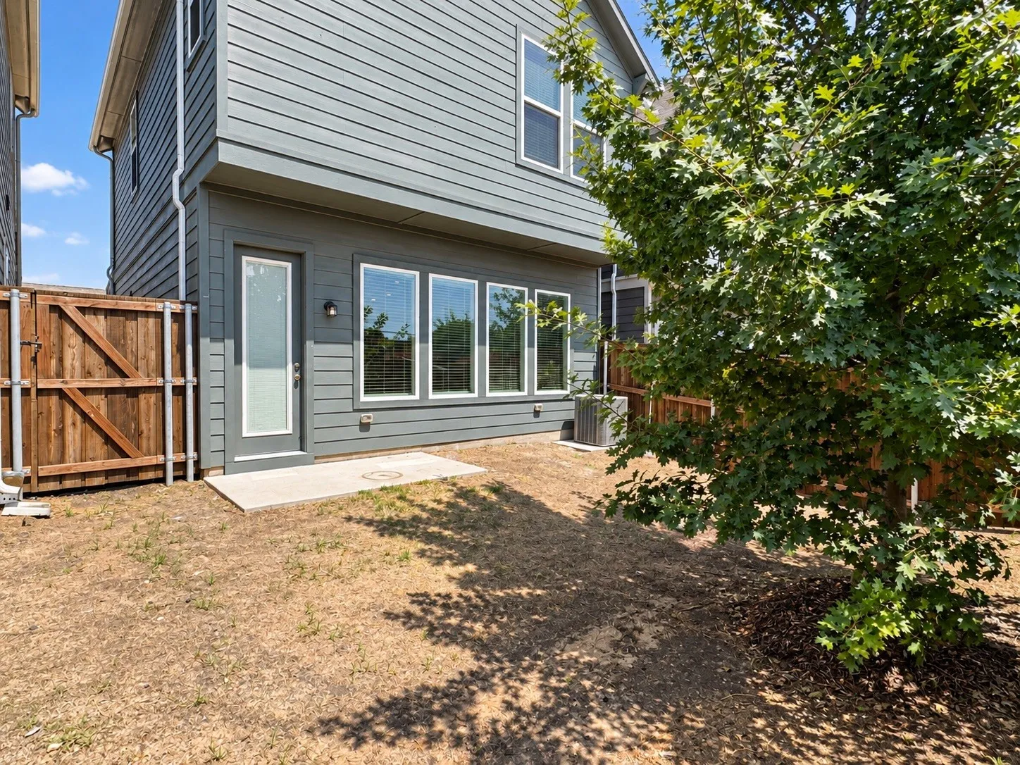 Rear exterior featuring horizontal siding, multiple windows, and a concrete patio