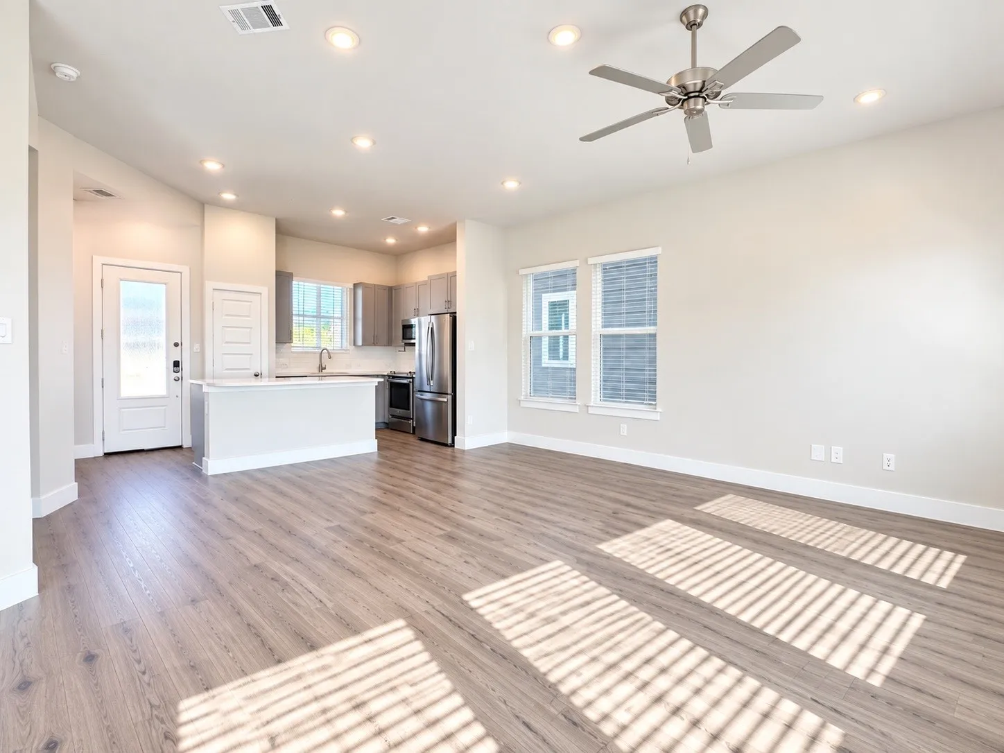Open-concept living area with wood-finish flooring, recessed lighting, and a ceiling fan