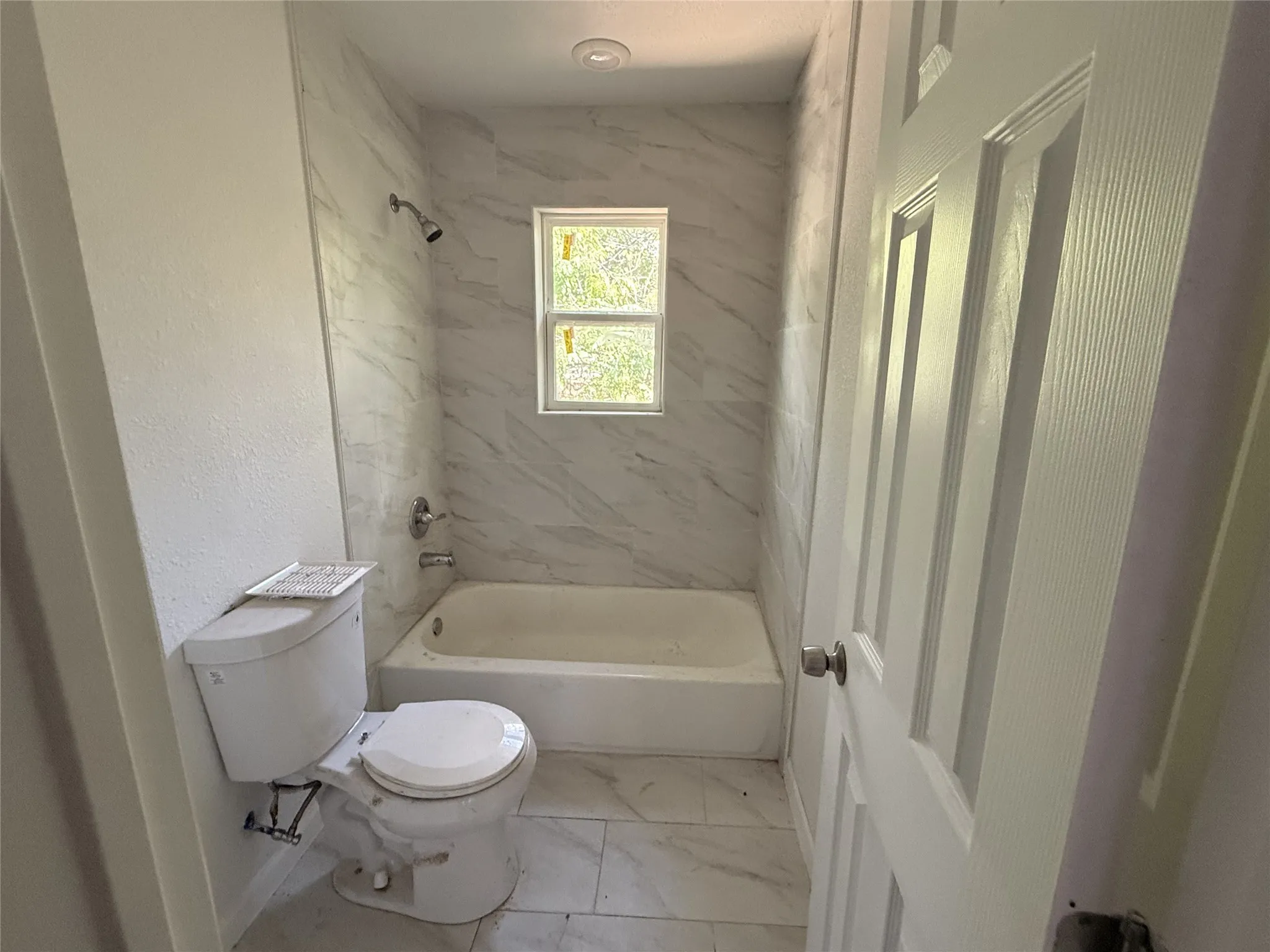 Bathroom featuring a white bathtub, tiled shower surround, recessed lighting, a window, and a white​​‌​​​​‌​​‌‌​‌‌​​​‌‌​‌​‌​‌​​​‌​​ toilet
