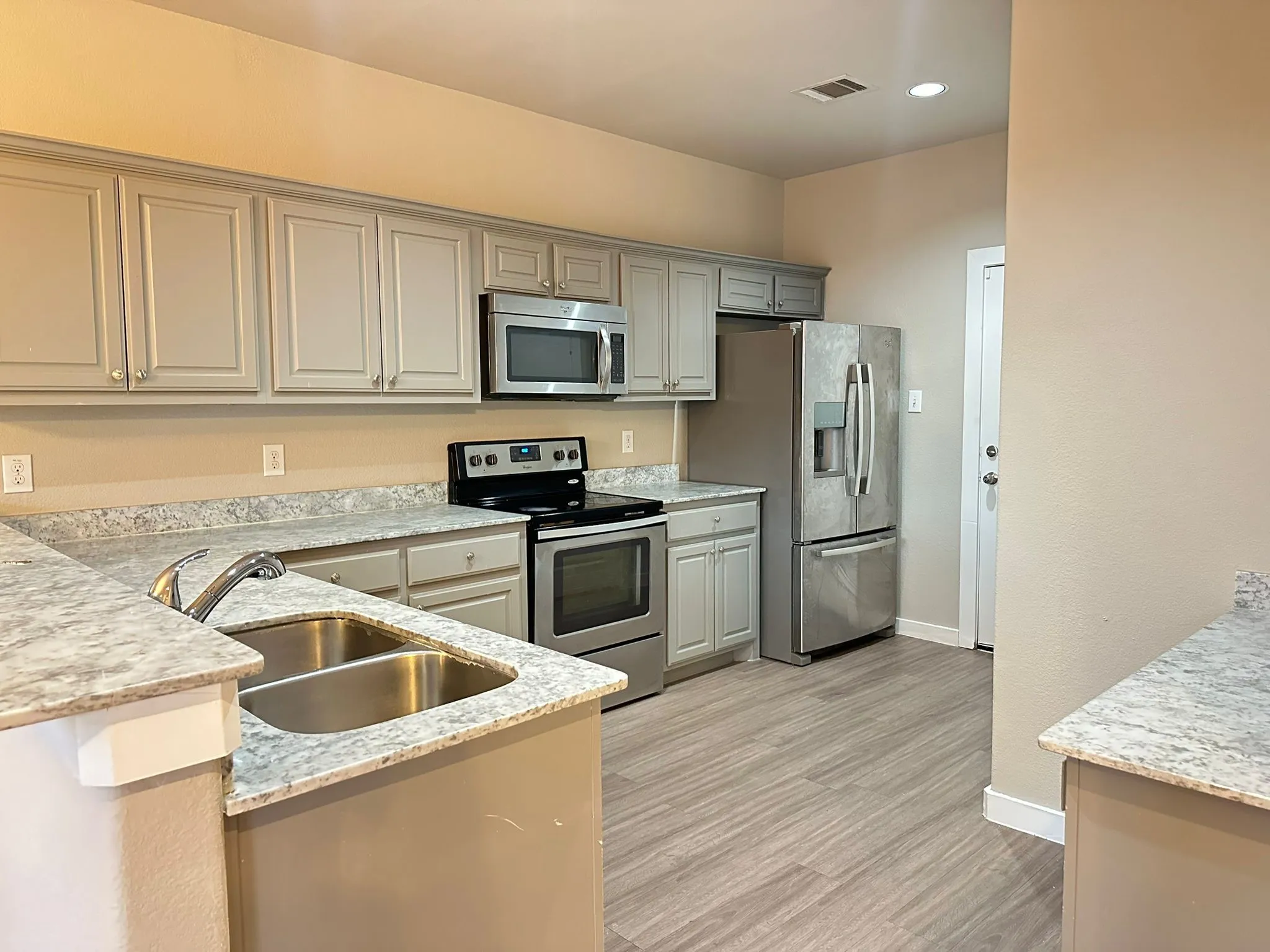 Light-toned cabinetry with coordinating counters, stainless steel appliances, and wood-finish flooring