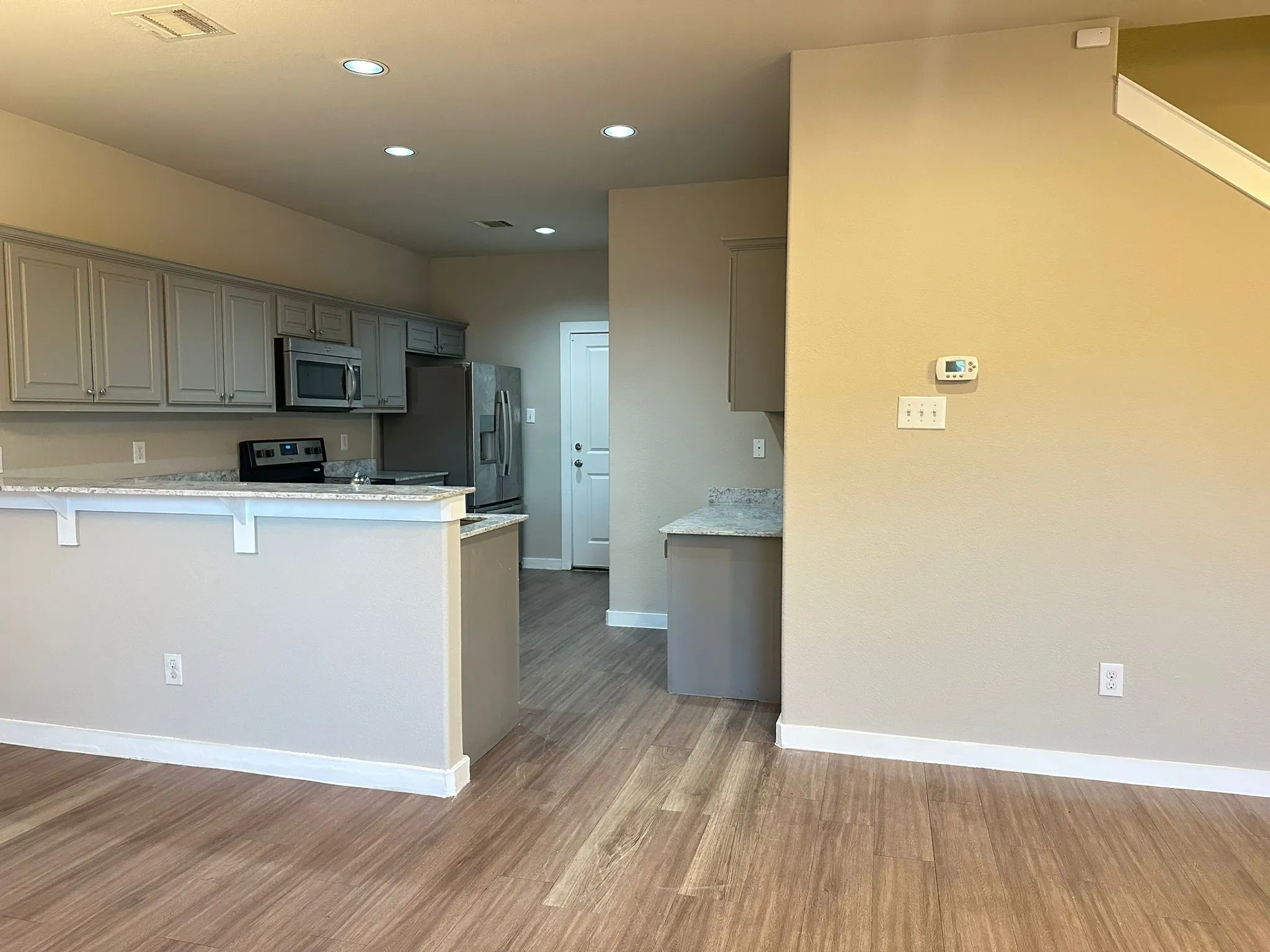 Open-concept kitchen featuring wood-finish flooring, recessed lighting, and grey cabinetry