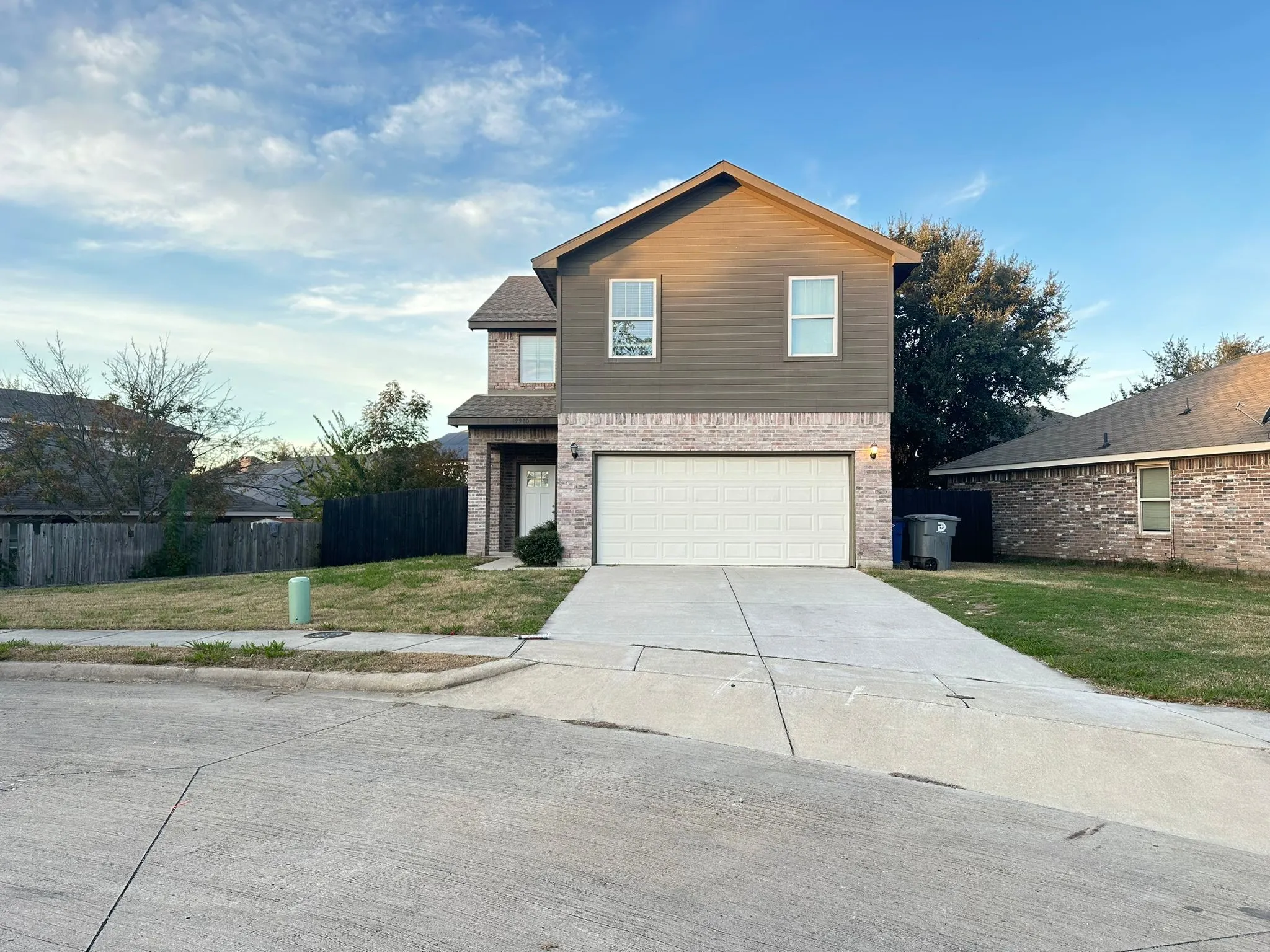 Two-story residence featuring a brick and siding exterior, an attached garage, and a concrete driveway