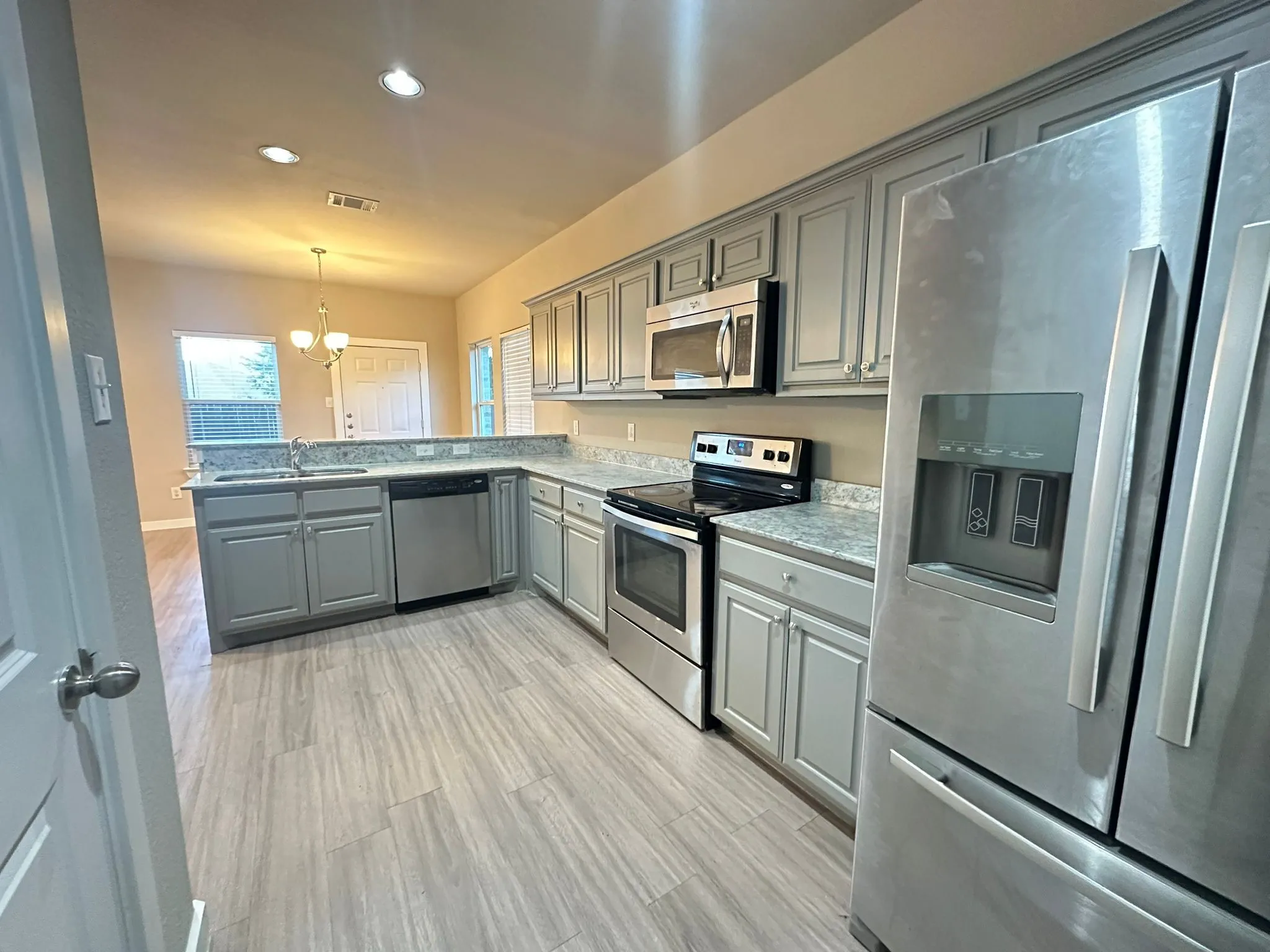 Kitchen with light gray cabinetry, stainless steel appliances, light-toned countertops, and wood-finish flooring