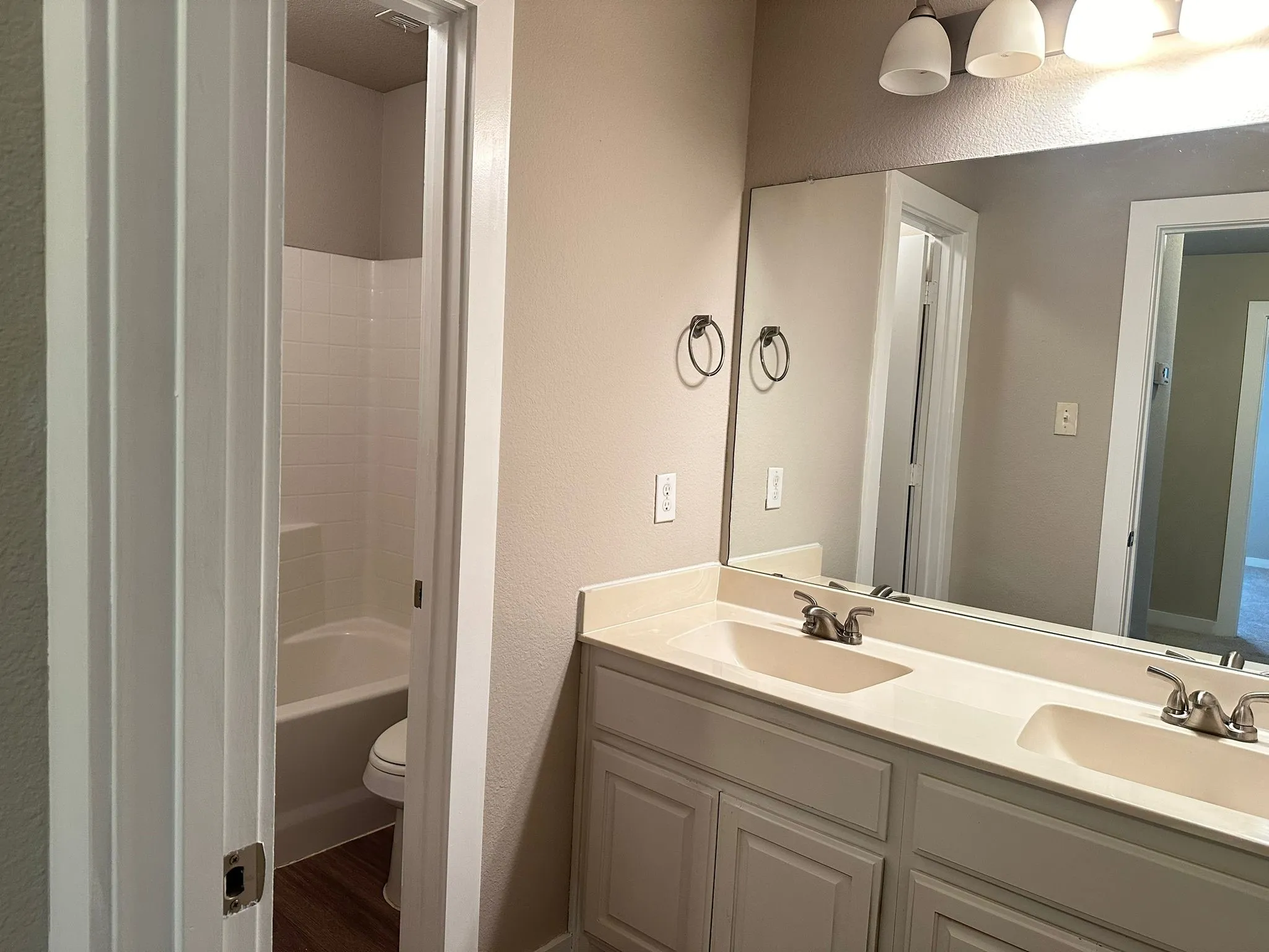Double vanity with integrated sinks, full-width mirror, and overhead light fixture