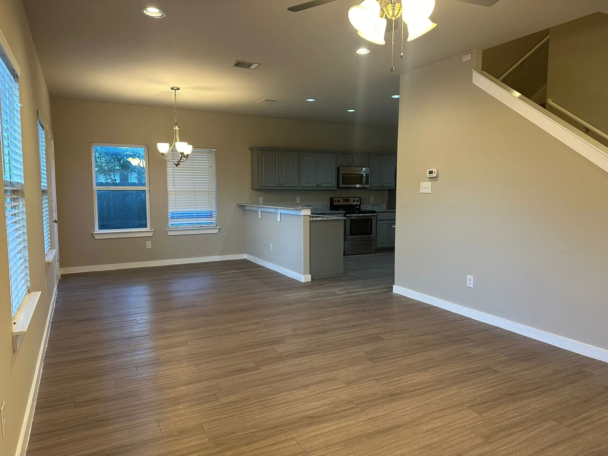 Wood-finish flooring throughout, recessed lighting, and a kitchen with stainless steel appliances