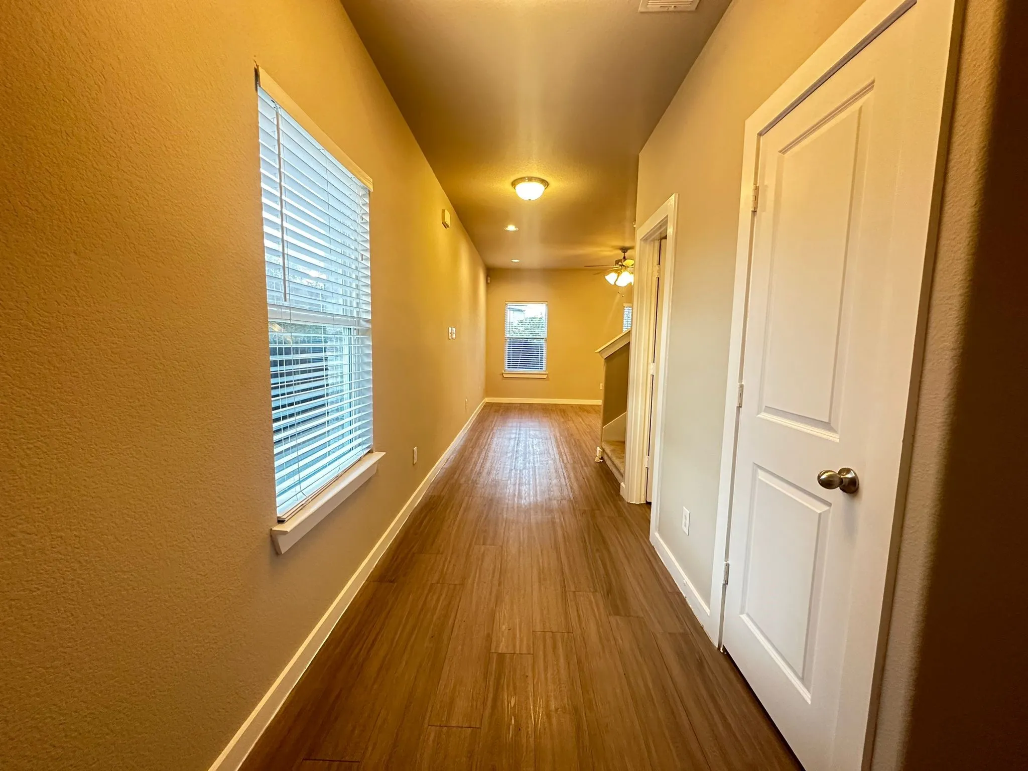 Wood-finish flooring throughout, multiple windows with blinds, recessed lighting, and panel doors
