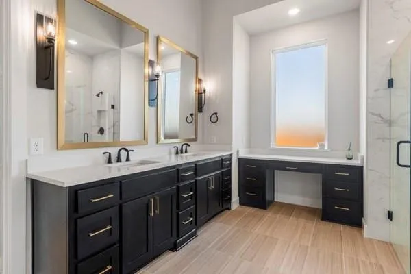 Dual vanity with white countertops, dark wood-finish cabinetry, and gold-framed mirrors
