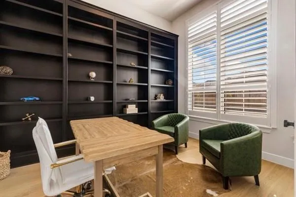 Custom built-in shelving, natural wood-finish flooring, and white plantation shutters