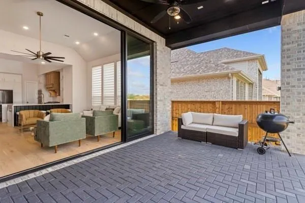 Covered patio featuring herringbone pattern paver flooring and a wood fence