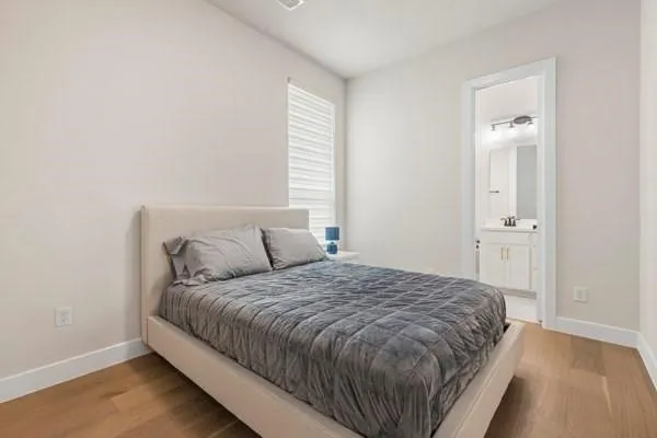 Hardwood-finish flooring, white walls, window with blinds, and white trim