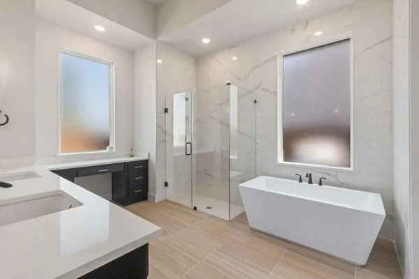 Dual vanity with white countertops, freestanding soaking tub with black fixtures, walk-in shower with glass enclosure, large format wall tiling, and wood-finish flooring