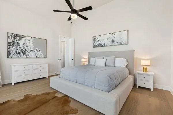 Vaulted ceiling with a ceiling fan, white paneled walls, wood-finish flooring, and white trim