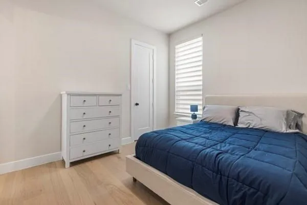 Wood-finish flooring, white walls, and a recessed ceiling vent