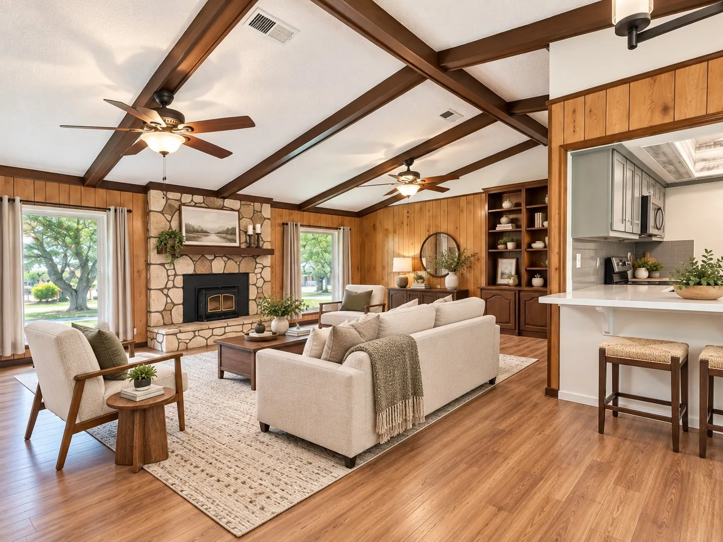 Vaulted ceiling with wood beams, stone fireplace with hearth, wood-finish flooring, built-in shelving, and a kitchen pass-through with breakfast bar