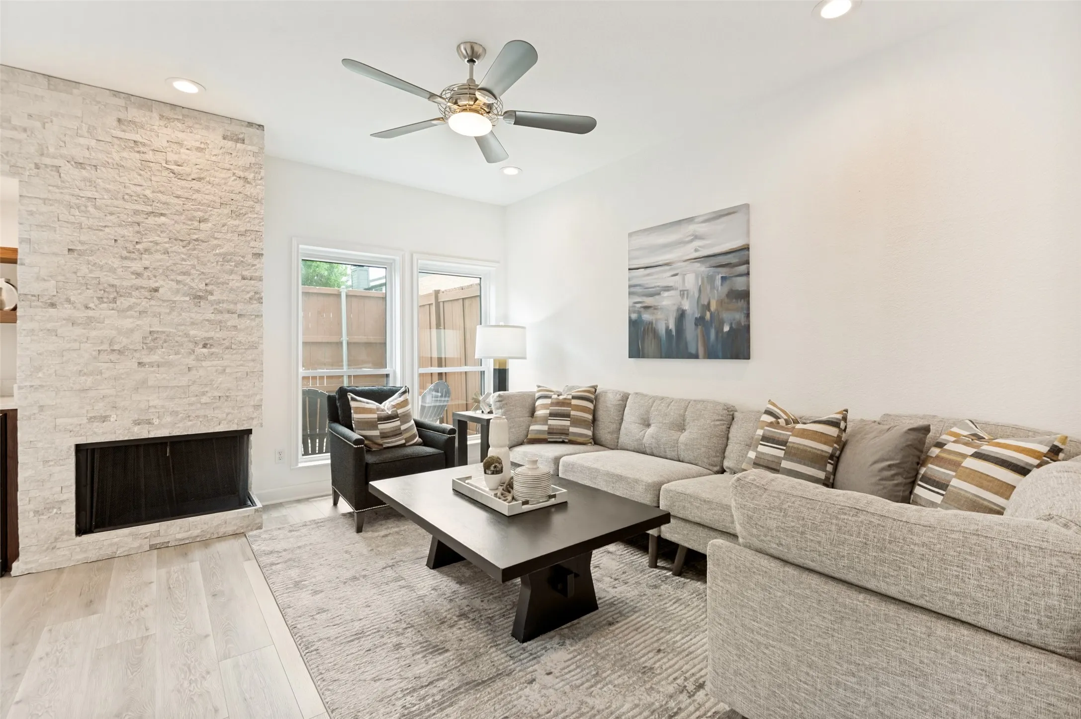 
This inviting living room is designed for both comfort and style, featuring high ceilings, recessed lighting, abundant natural light, and a striking floor-to-ceiling stone, wood-burning fireplace that serves as the focal point of the space.
