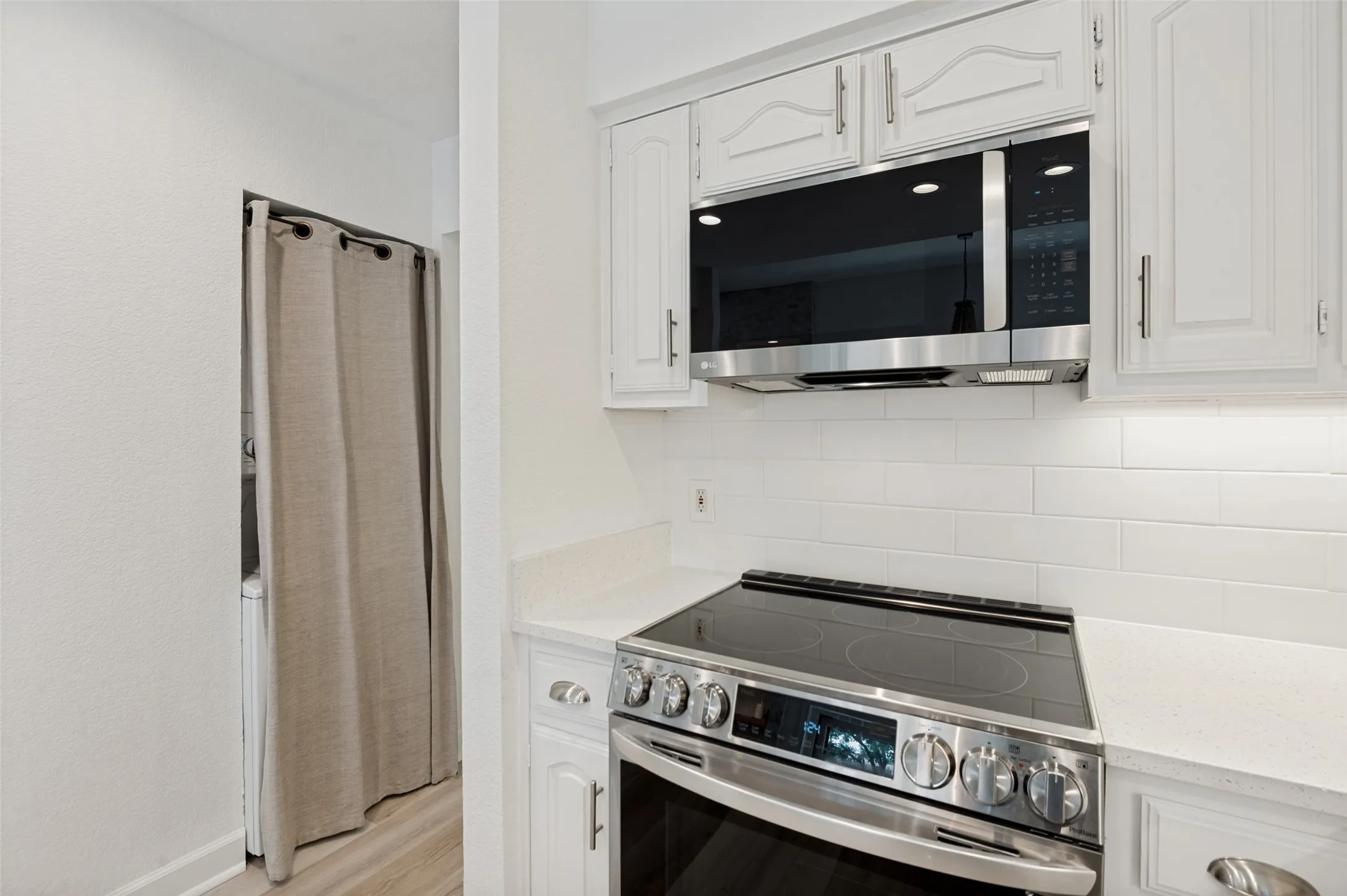 Conveniently tucked just off the kitchen, the dedicated laundry area features a stacked washer and dryer, maximizing functionality while preserving valuable living space. Thoughtfully concealed behind decorative drapery, this hidden laundry nook blends seamlessly into the home's design, keeping everyday necessities out of sight while remaining easily accessible.