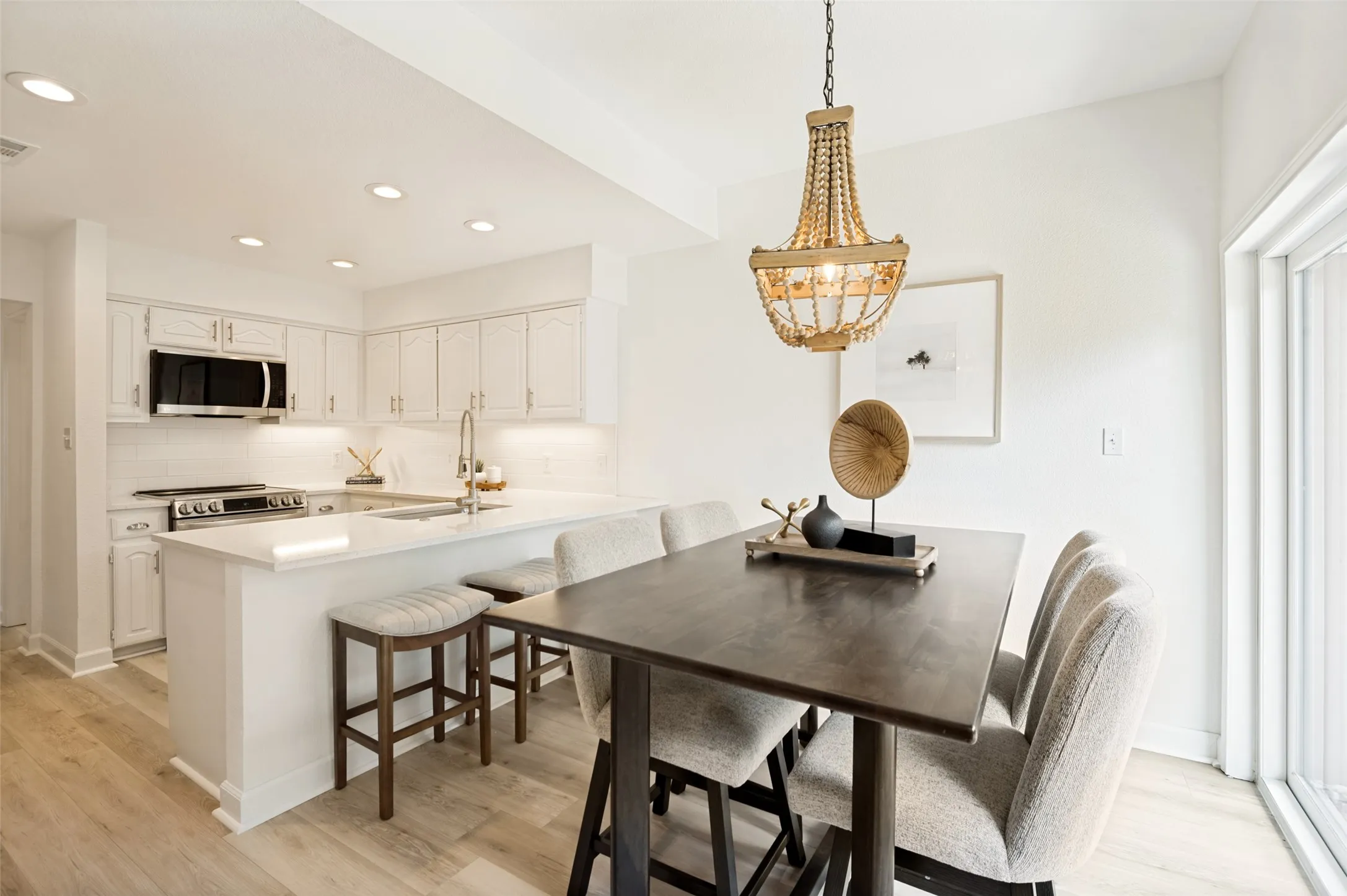 This bright and inviting dining area is perfectly positioned between the kitchen and outdoor patio, creating a seamless flow for both everyday living and entertaining. Large sliding glass doors fill the space with natural light, enhancing the airy atmosphere and offering easy access to outdoor dining and relaxation. The elegant chandelier adds a touch of warmth and sophistication.