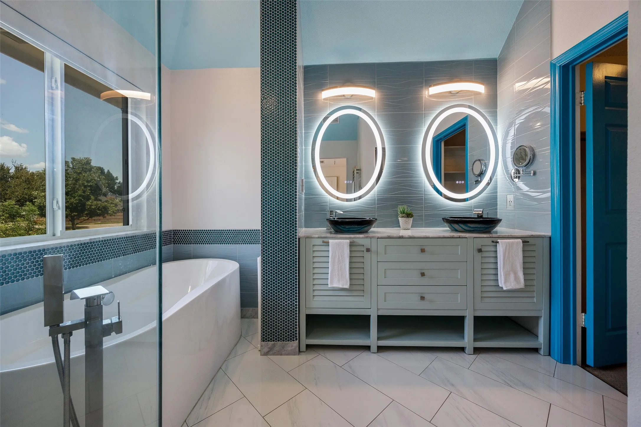 Dual vanity with vessel sinks and integrated back-lit mirrors, freestanding soaking tub, and walk-in shower with glass enclosure. Heated floors, Heated Towel Rack, Electric Window Shades.