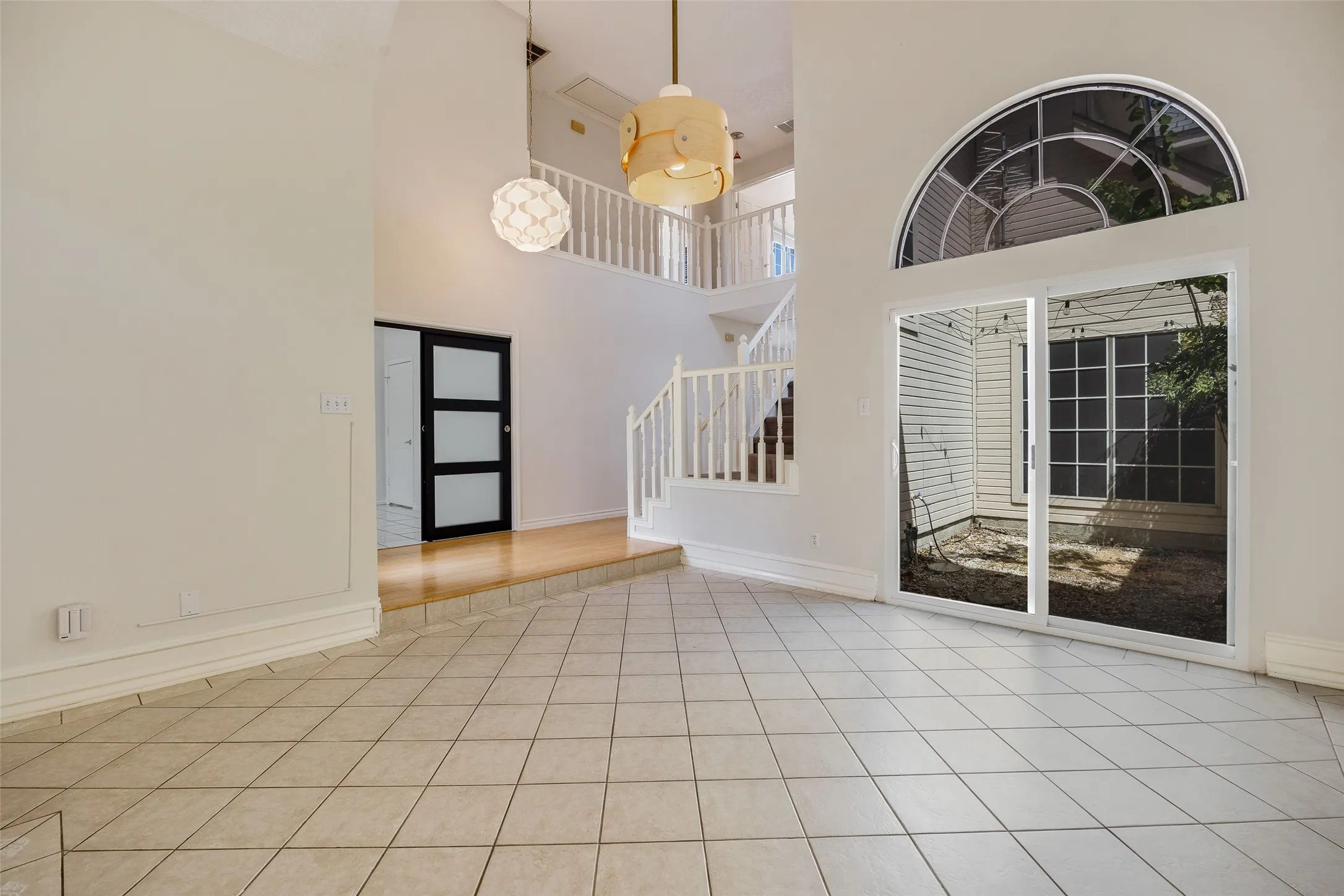 Two-story interior with tile flooring, wood-finish flooring, a contemporary sliding barn door, and a built-in staircase with white railings