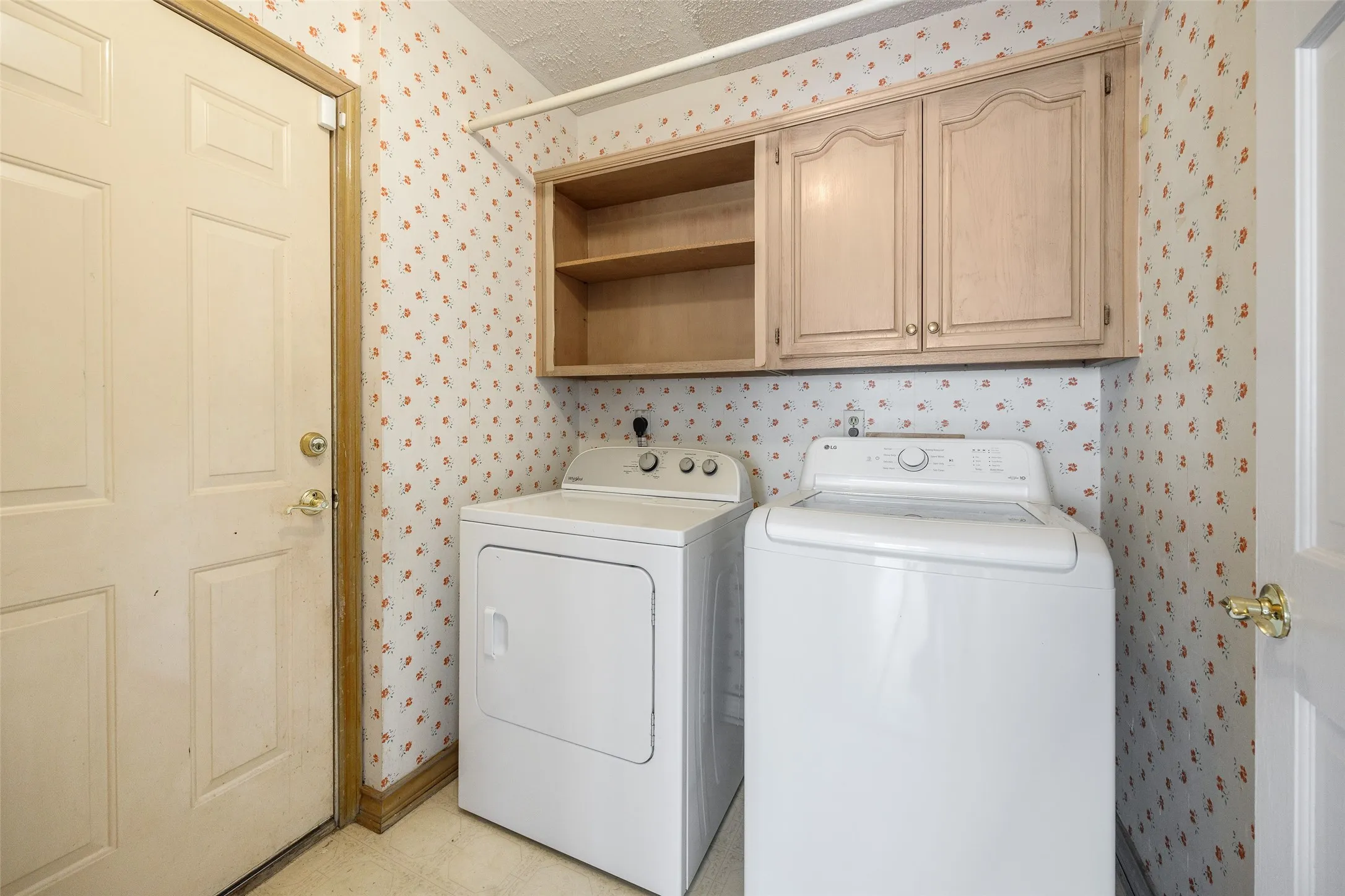 Laundry area featuring upper cabinetry with open shelving and closed storage, and a paneled door