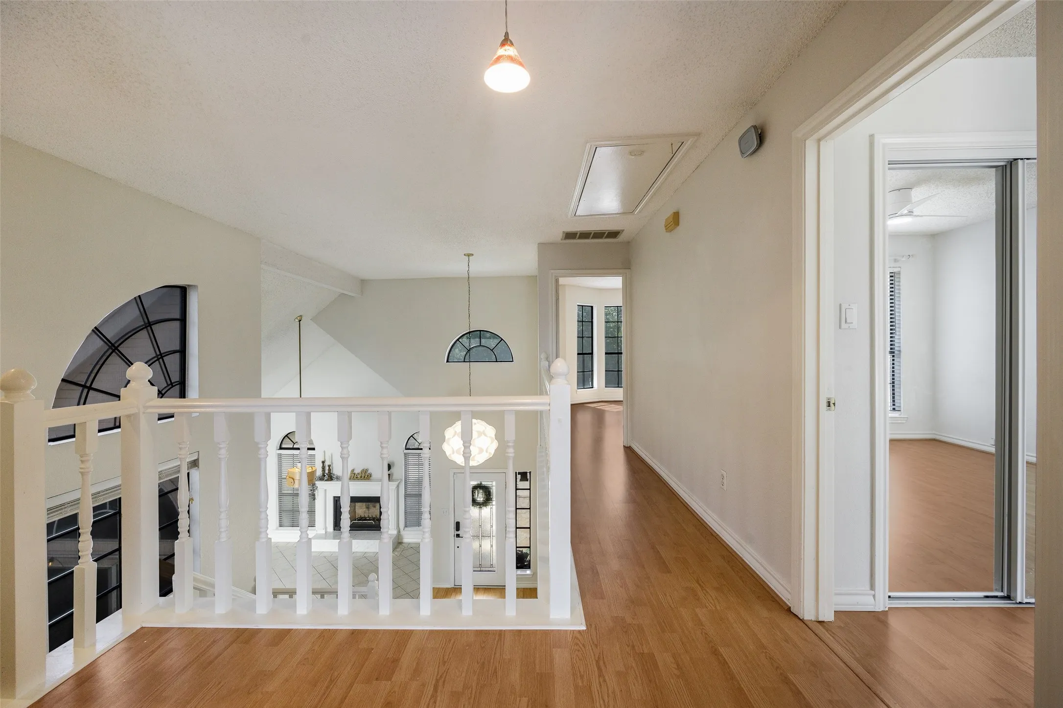 Wood-finish flooring throughout, white baluster railing, arched windows, and vaulted ceilings