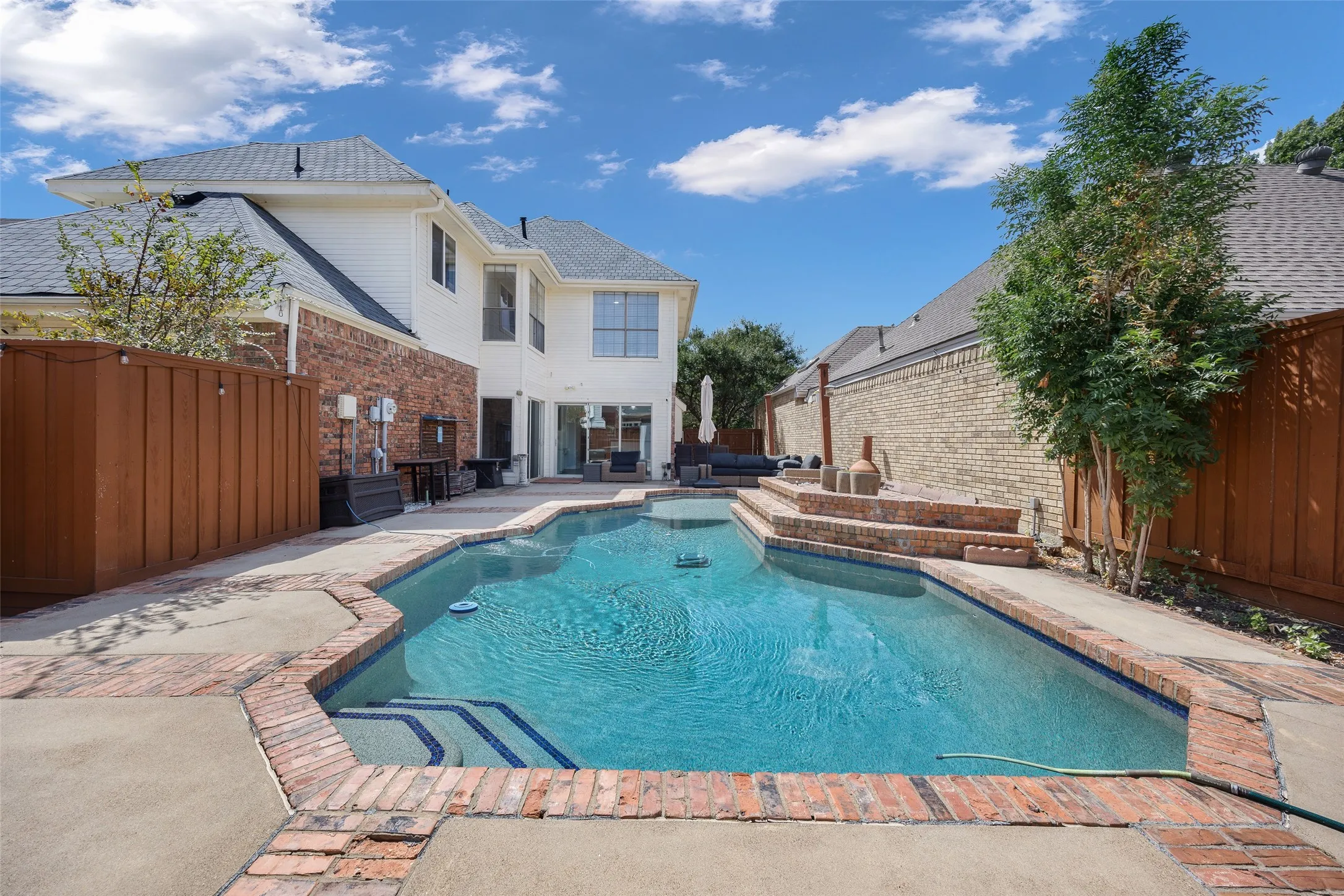 Resort-style pool with integrated steps, brick coping, and a surrounding patio