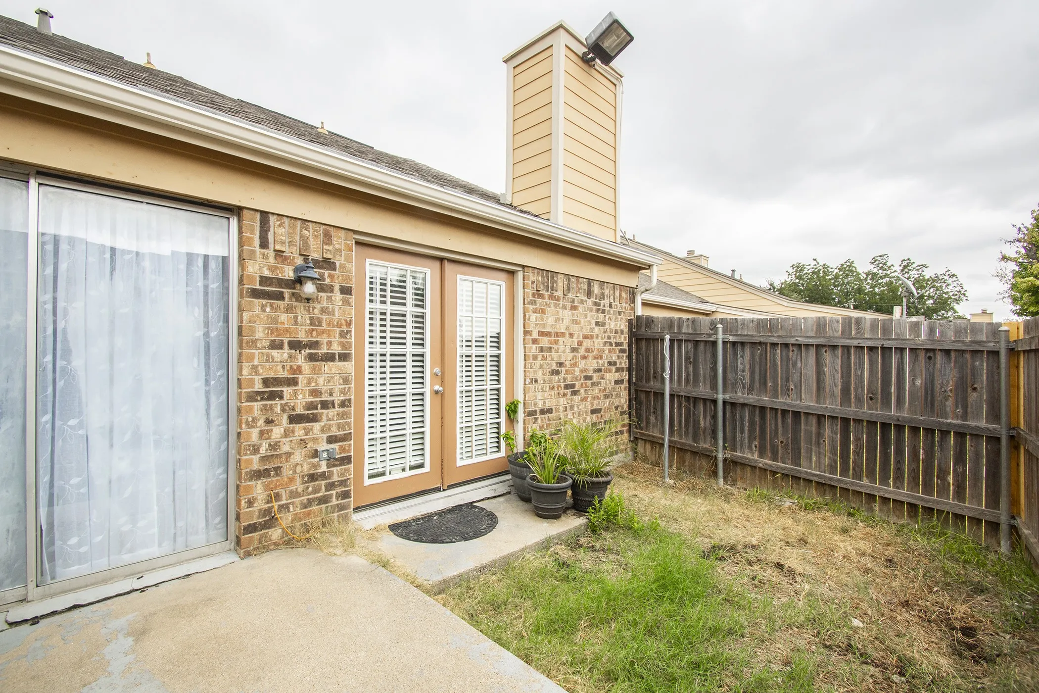 Private enclosed yard featuring a wooden privacy fence, concrete patio, and brick exterior