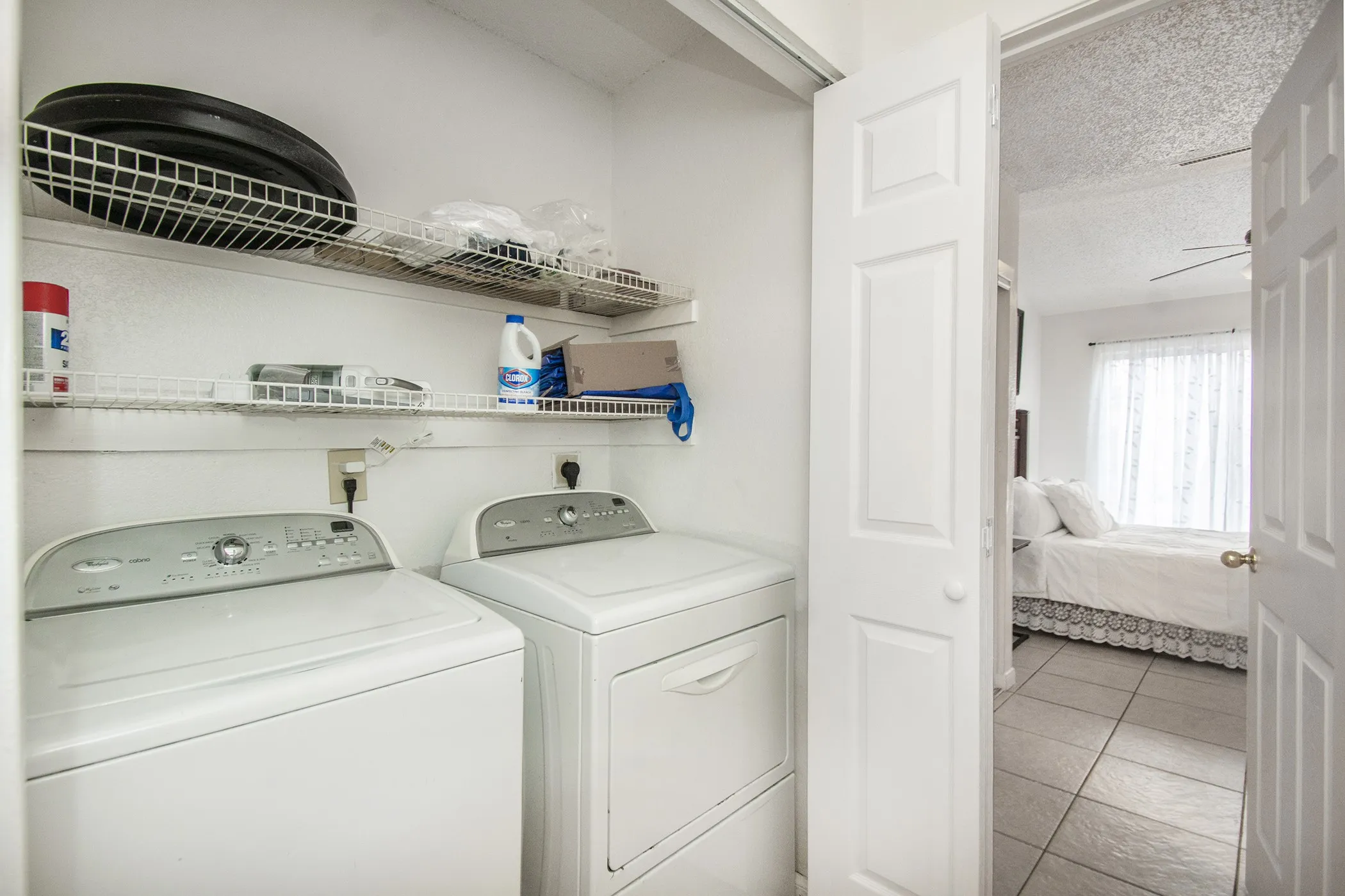 Integrated laundry area with white appliances and built-in wire shelving