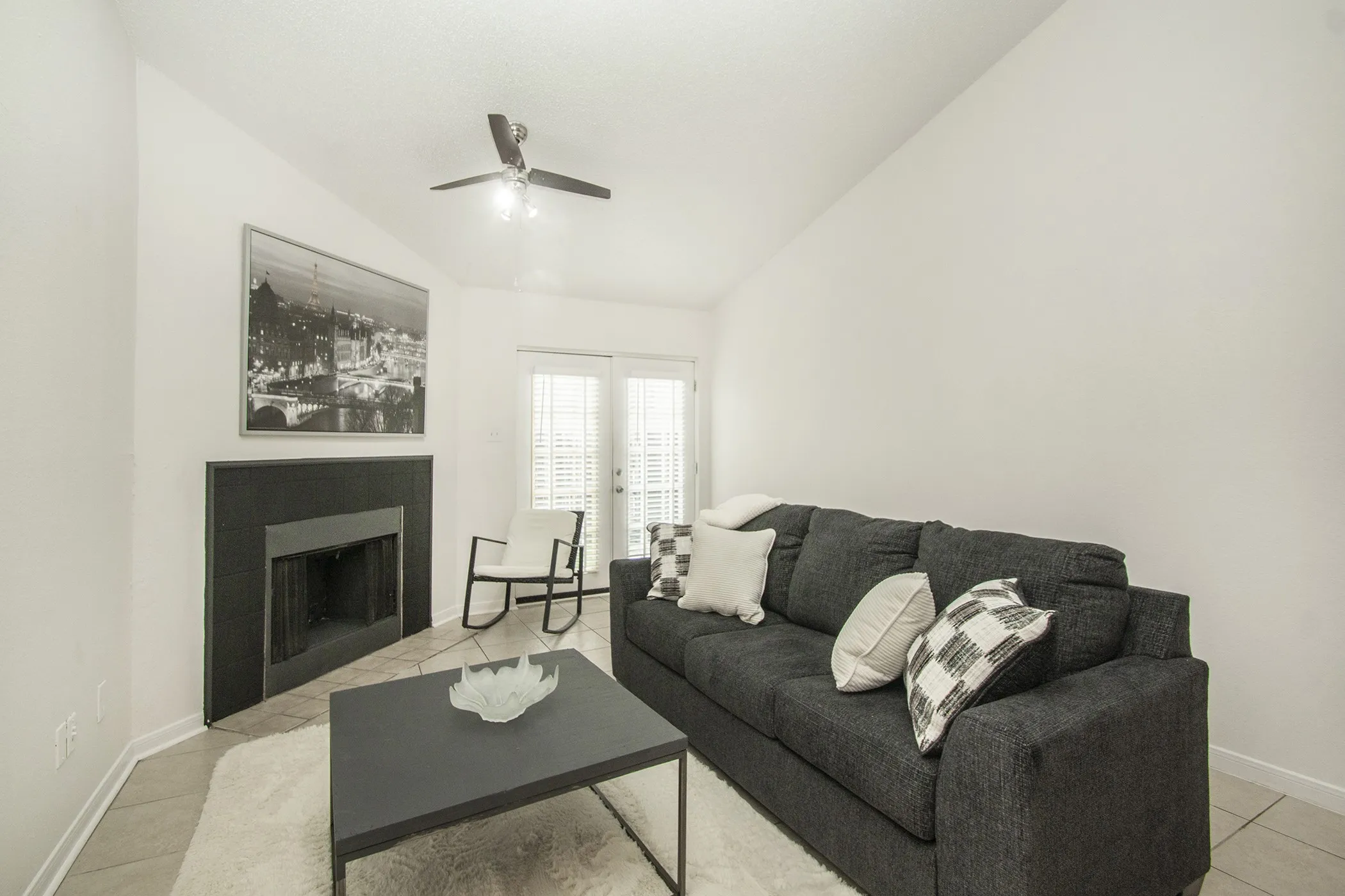 Vaulted ceilings, a built-in fireplace, ceiling fan, tile flooring, and French doors