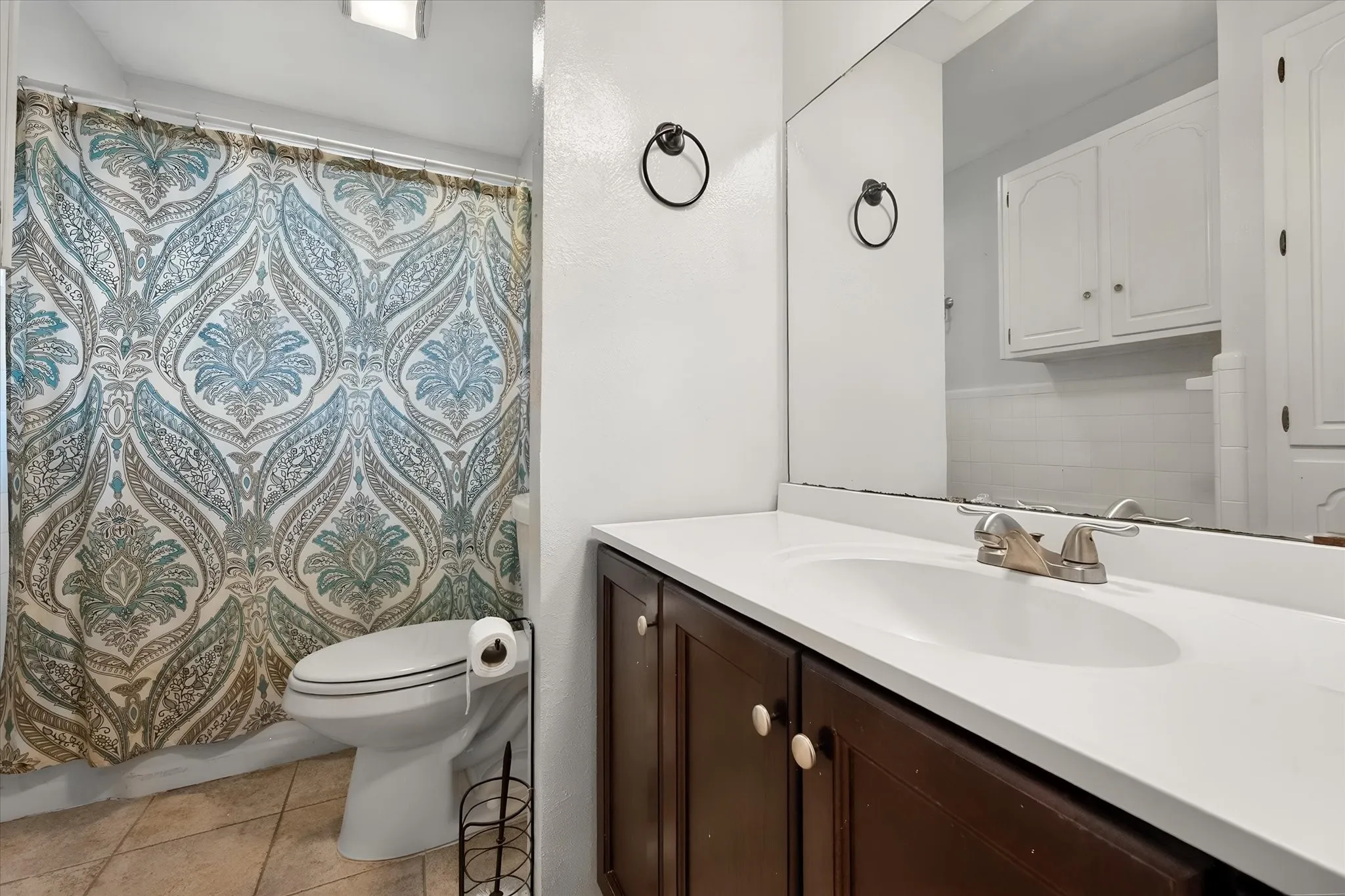 Undermount sink with a brushed nickel faucet, large vanity mirror, and white upper cabinetry