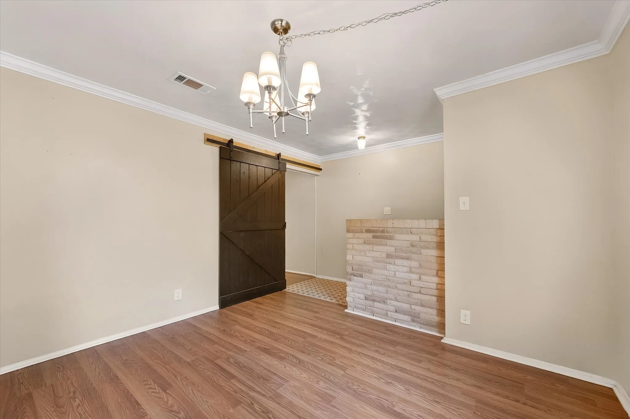 Wood-finish flooring with crown molding and white baseboards