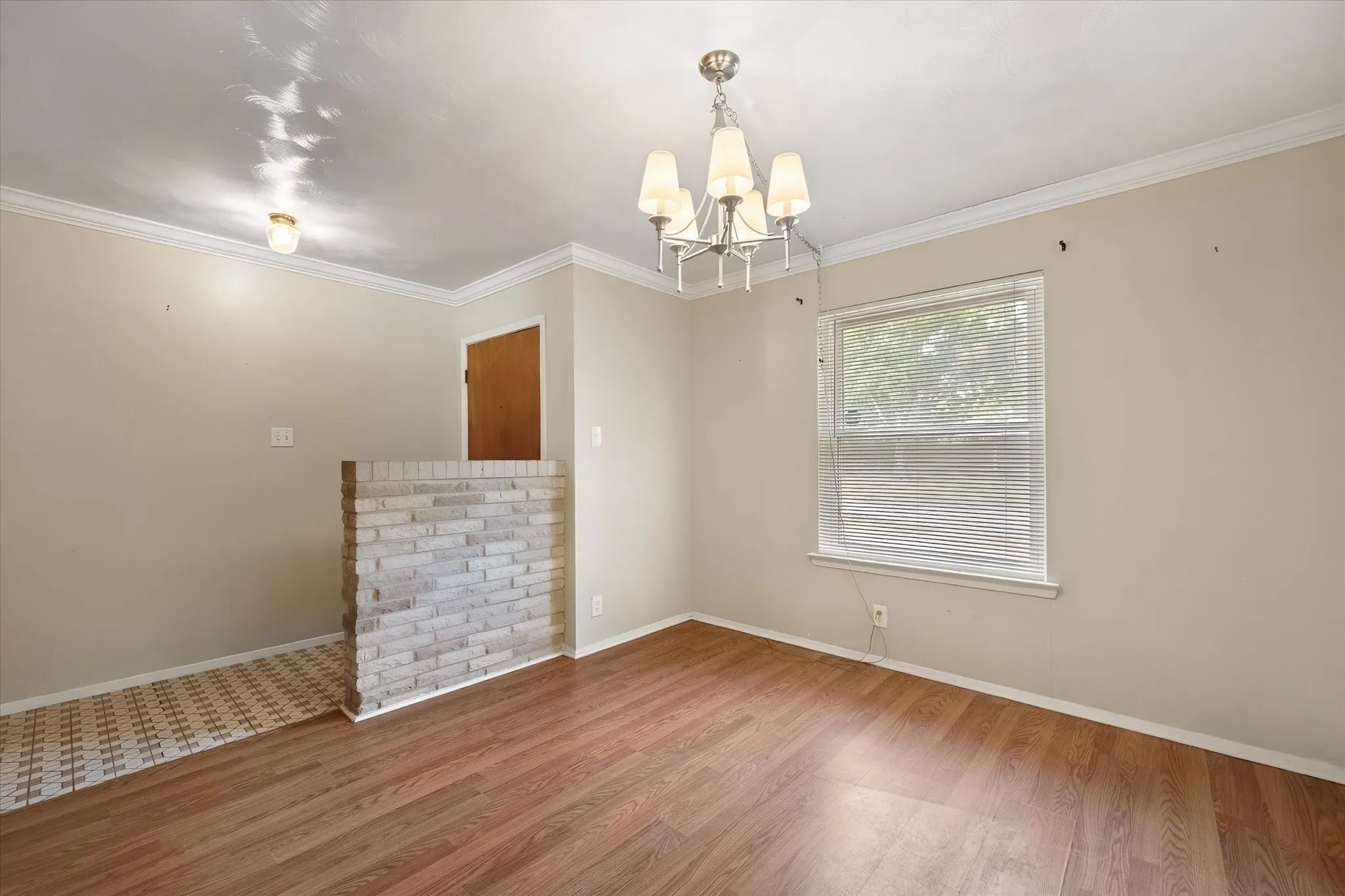 Wood-finish flooring, half-height brick wall, ceiling-mounted light fixture, recessed lighting, and crown molding