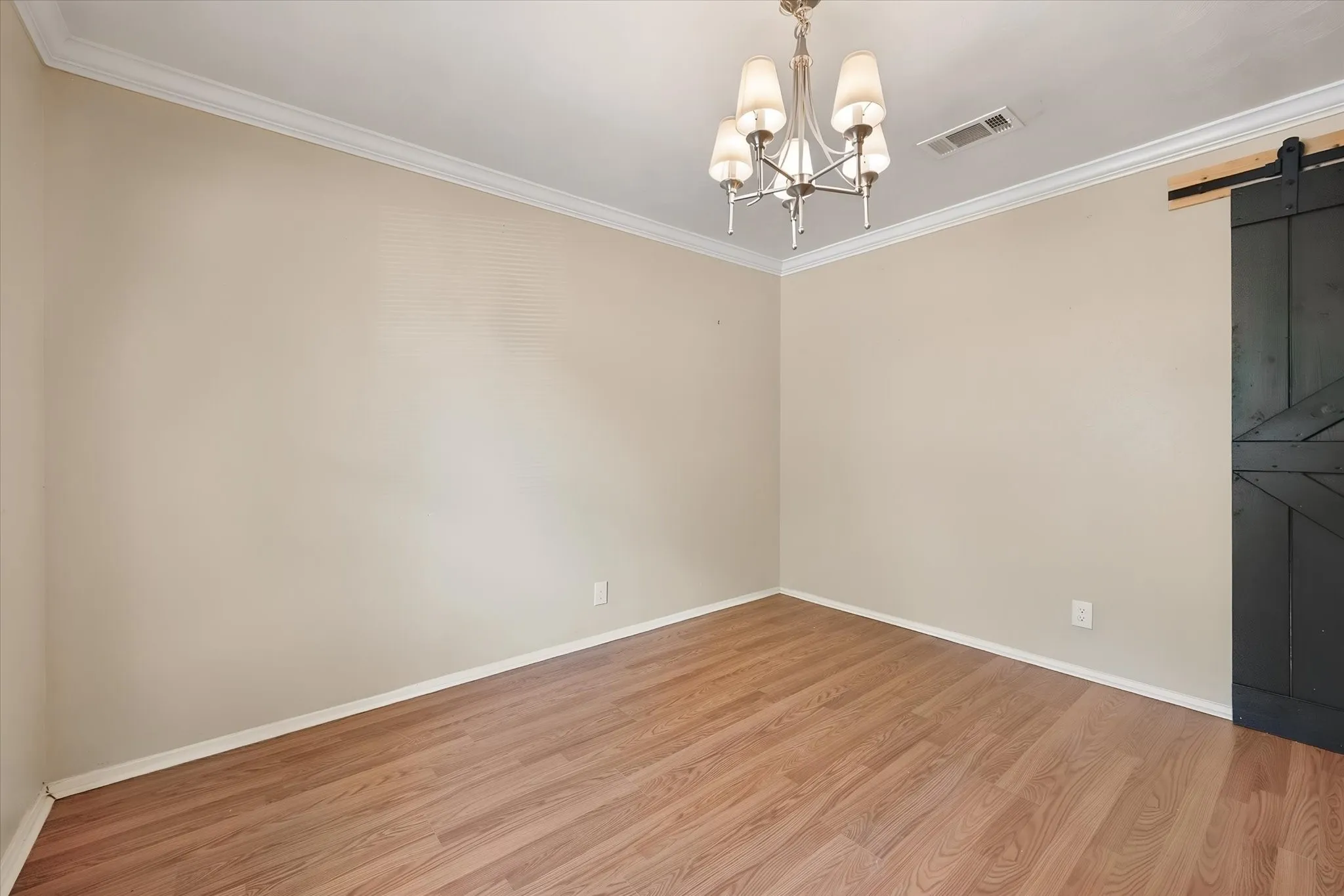 Wood-finish flooring, crown molding, and a five-light chandelier complement the neutral wall tones