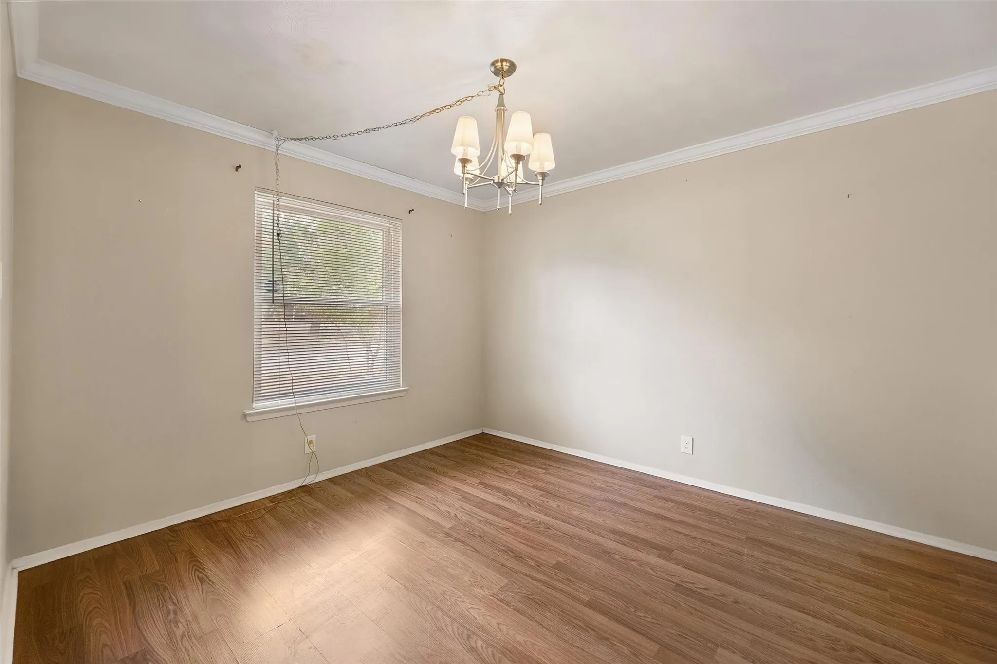 Recessed window with blinds, wood-finish flooring, and crown molding