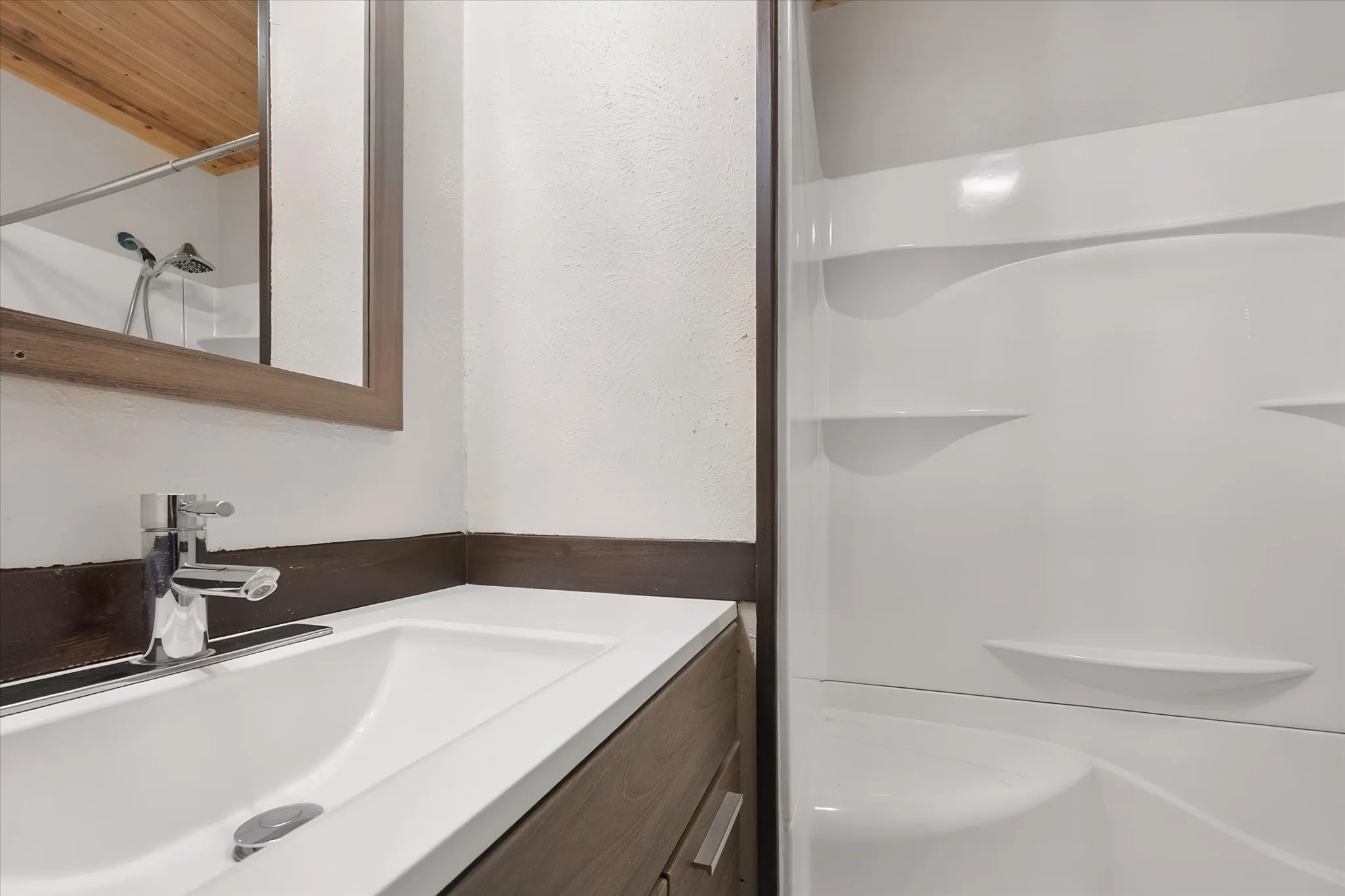 White single basin sink with a chrome faucet, set into a dark wood-finish vanity