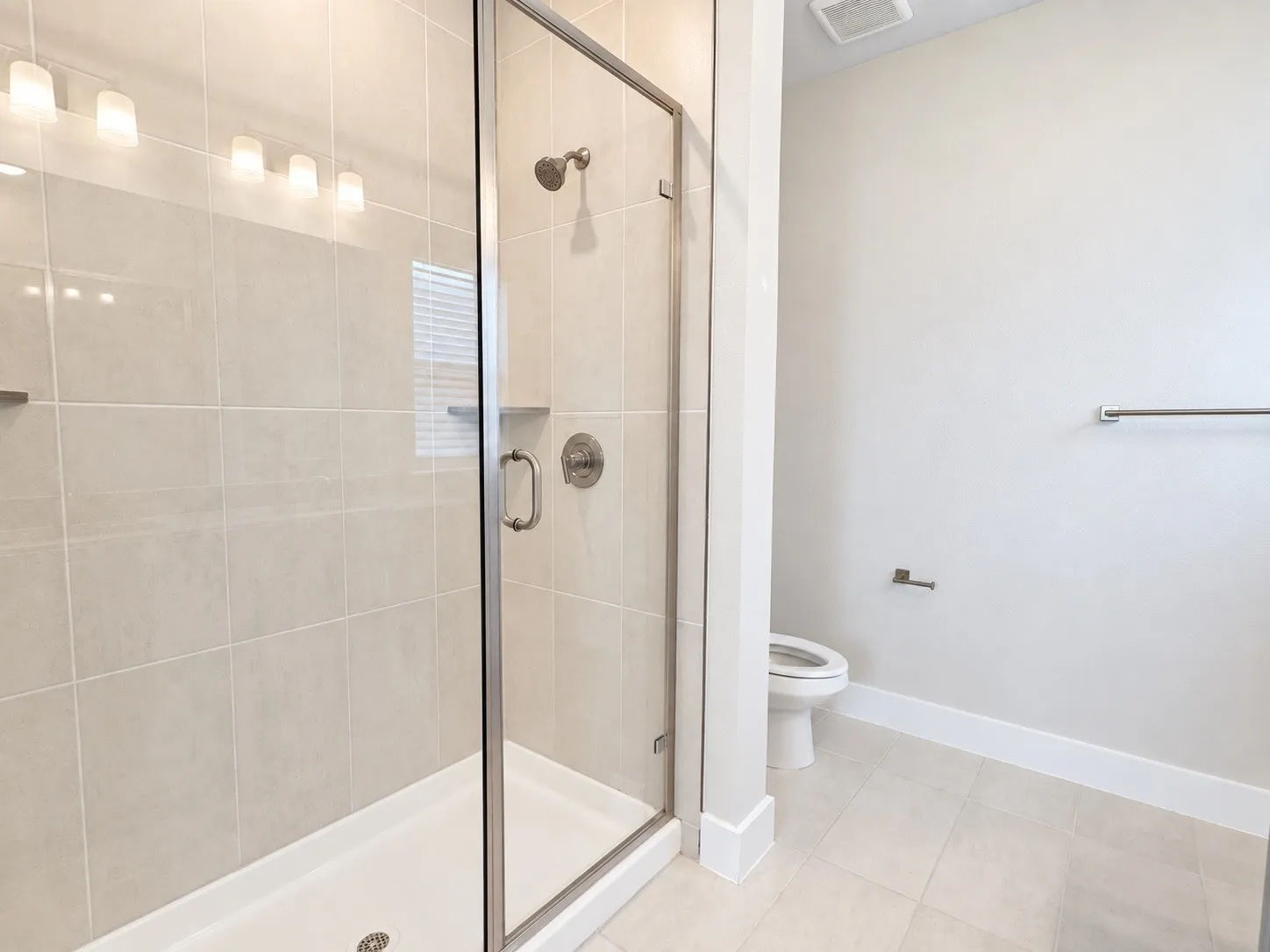 Glass-enclosed shower with a tiled interior, chrome fixtures, and integrated shelving