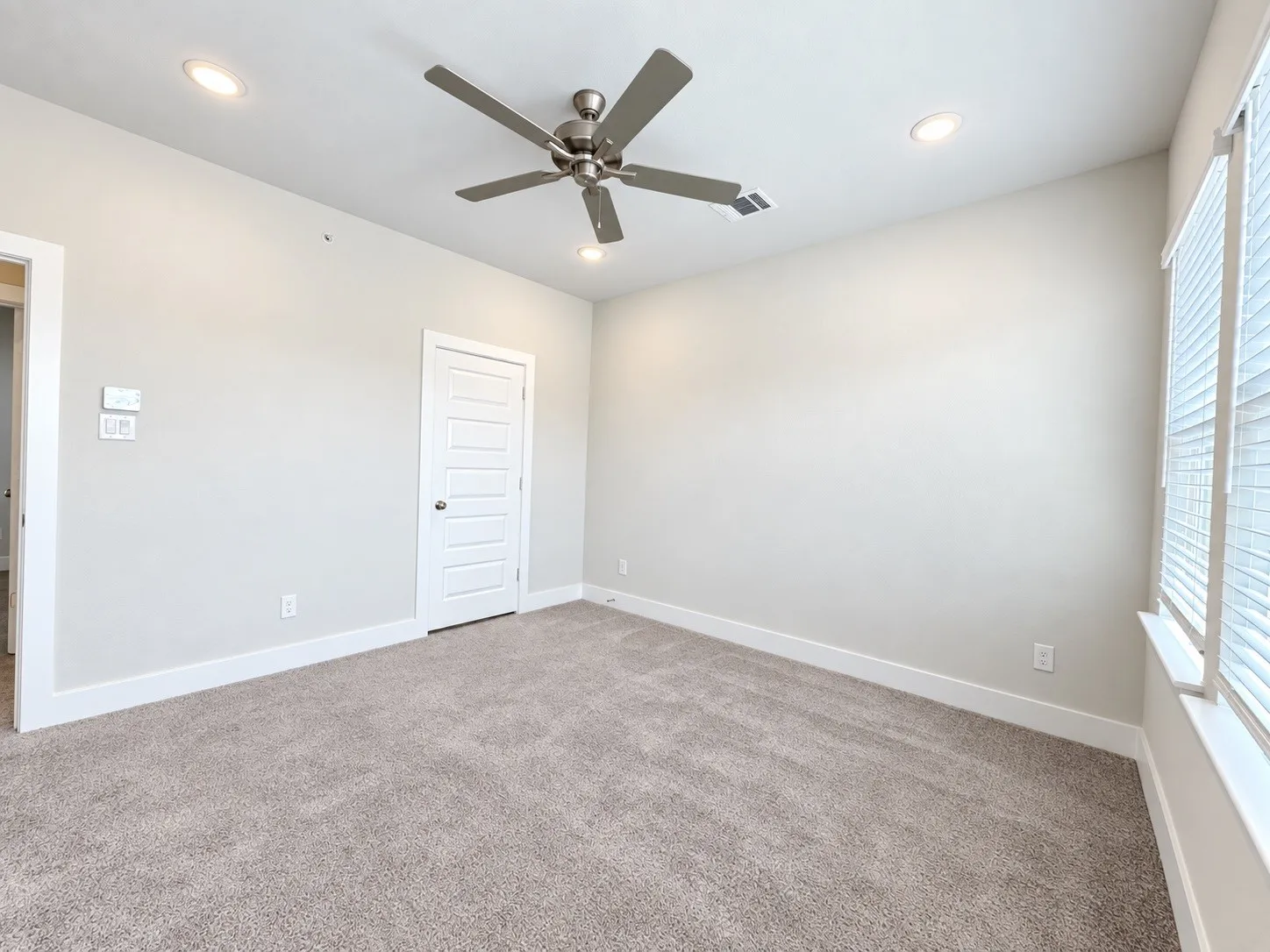Plush carpeting, recessed lighting, and a ceiling fan with brushed nickel accents