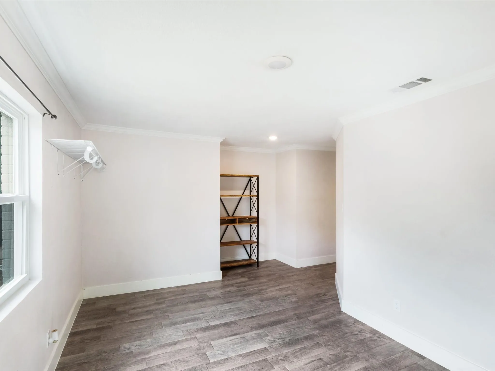 Wood-finish flooring, white walls, and a window with a white frame
