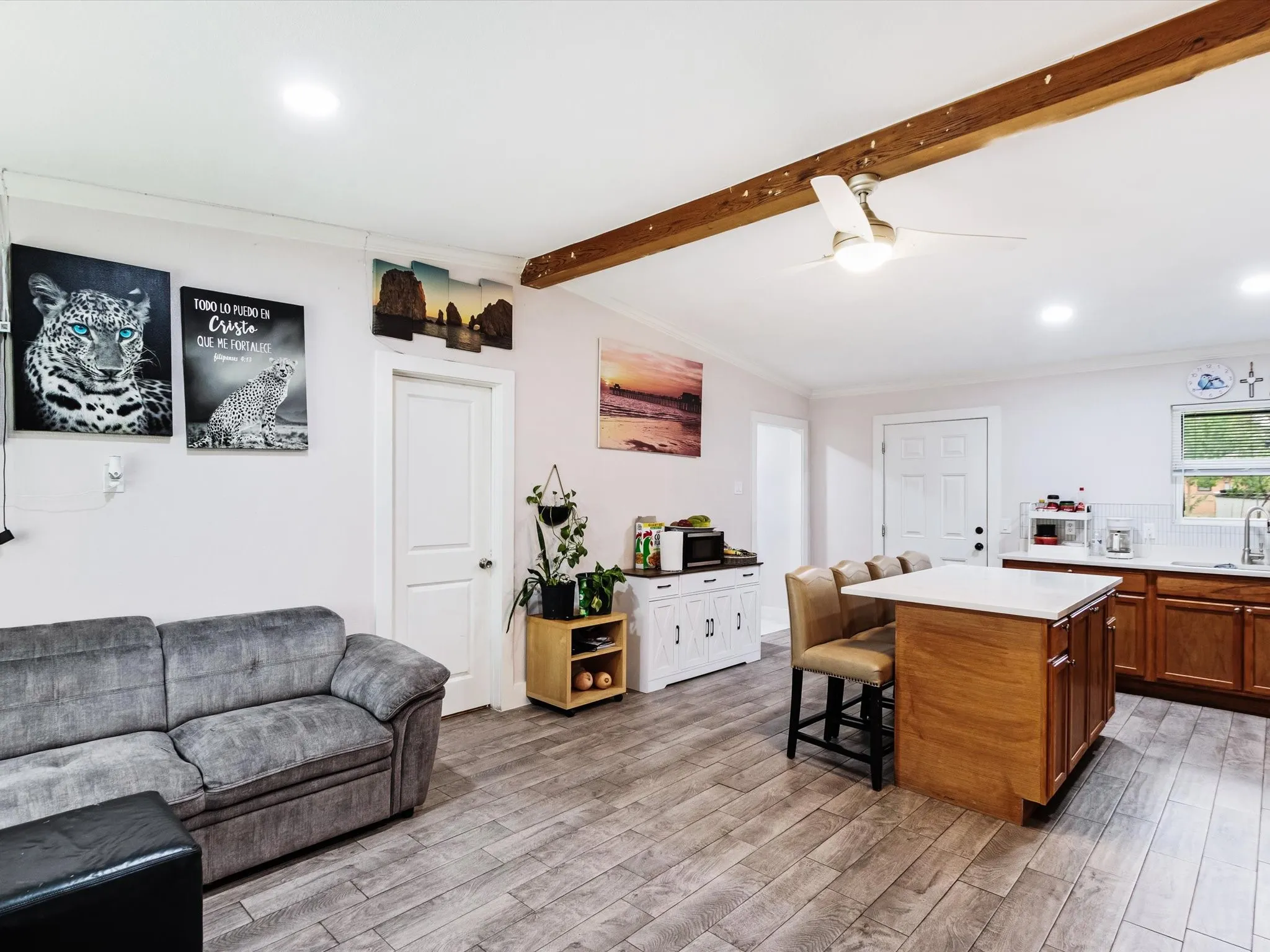 Vaulted ceiling with wood beam, recessed lighting, wood-finish flooring, central island with seating, and a white subway tile backsplash