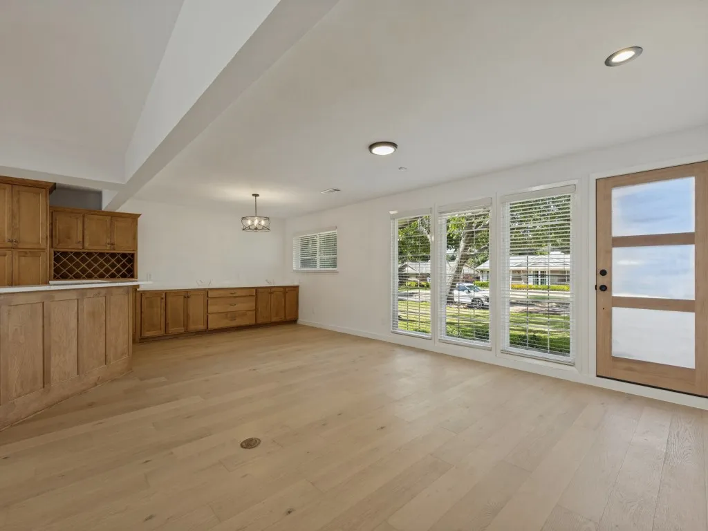 Wood-finish flooring throughout, featuring a built-in wet bar with wood cabinetry and wine storage