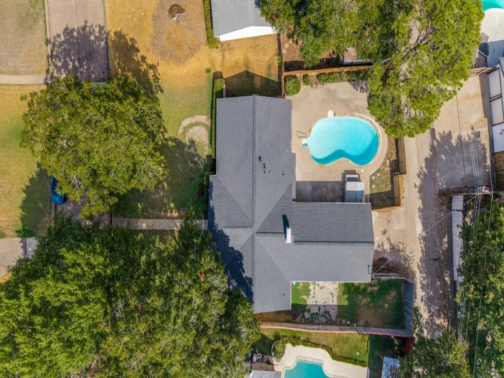 Asymmetrical roofline, multiple mature trees, two swimming pools, two hardscaped patio areas, and an expansive lawn