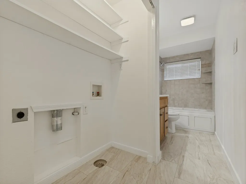 Laundry area with built-in shelving, tile flooring, and floor drain